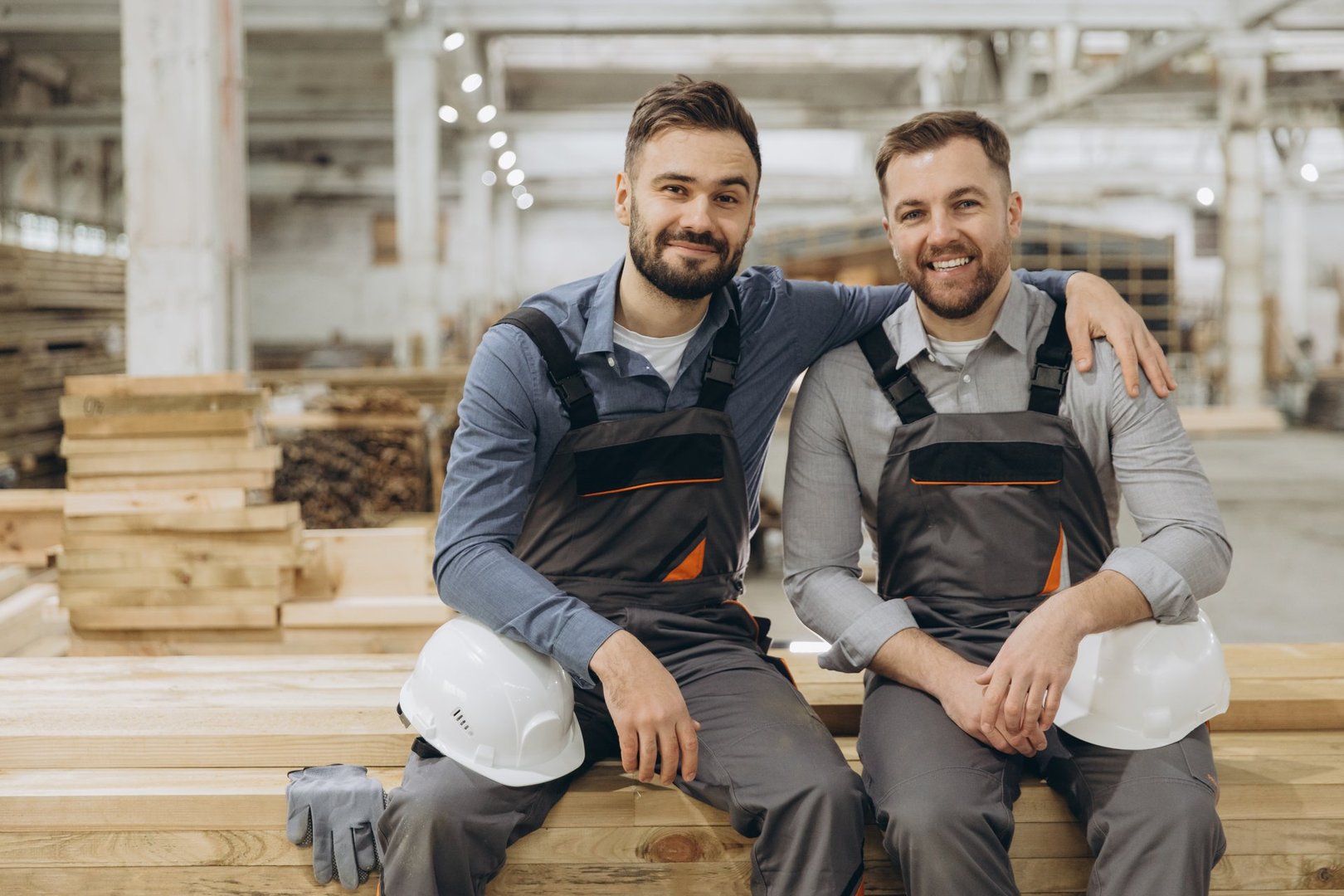 Two carpenters are taking a break and smiling in their timber warehouse