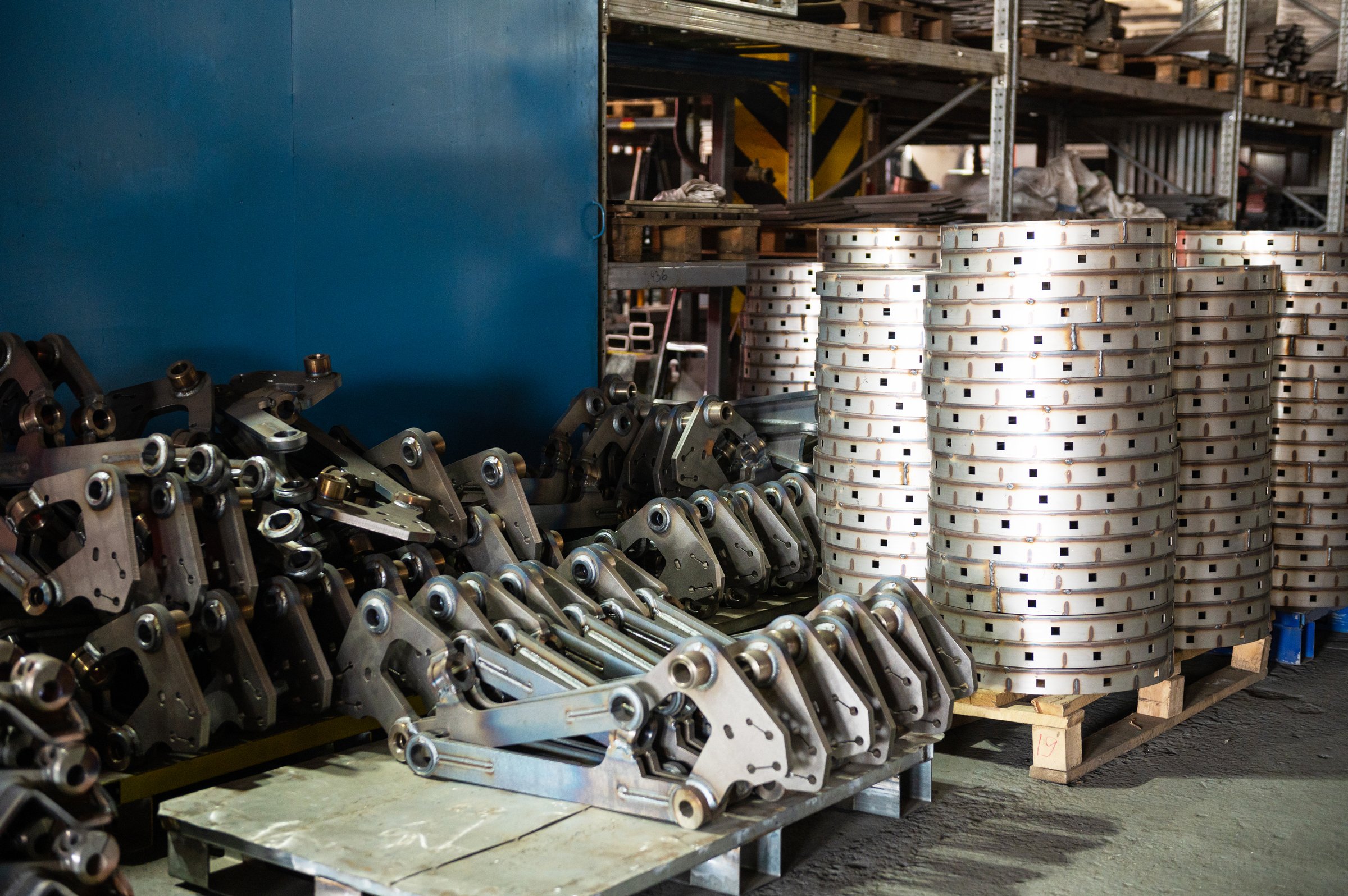 A factory storage area filled with stacks of industrial metal parts and components, ready for use in manufacturing or assembly.