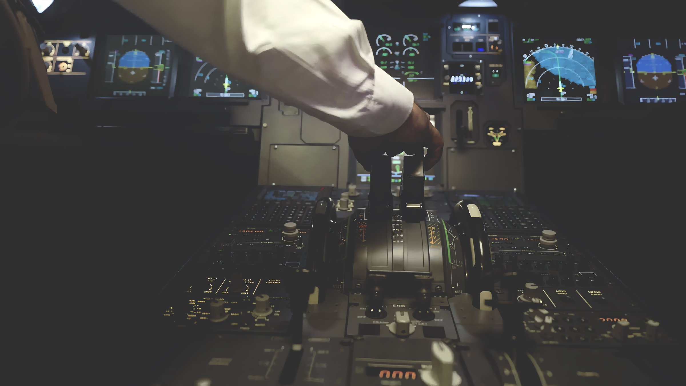 Pilot's hand operating the throttle levers inside a modern airplane cockpit, surrounded by illuminated controls and navigation screens, symbolizing precision and aviation expertise.
