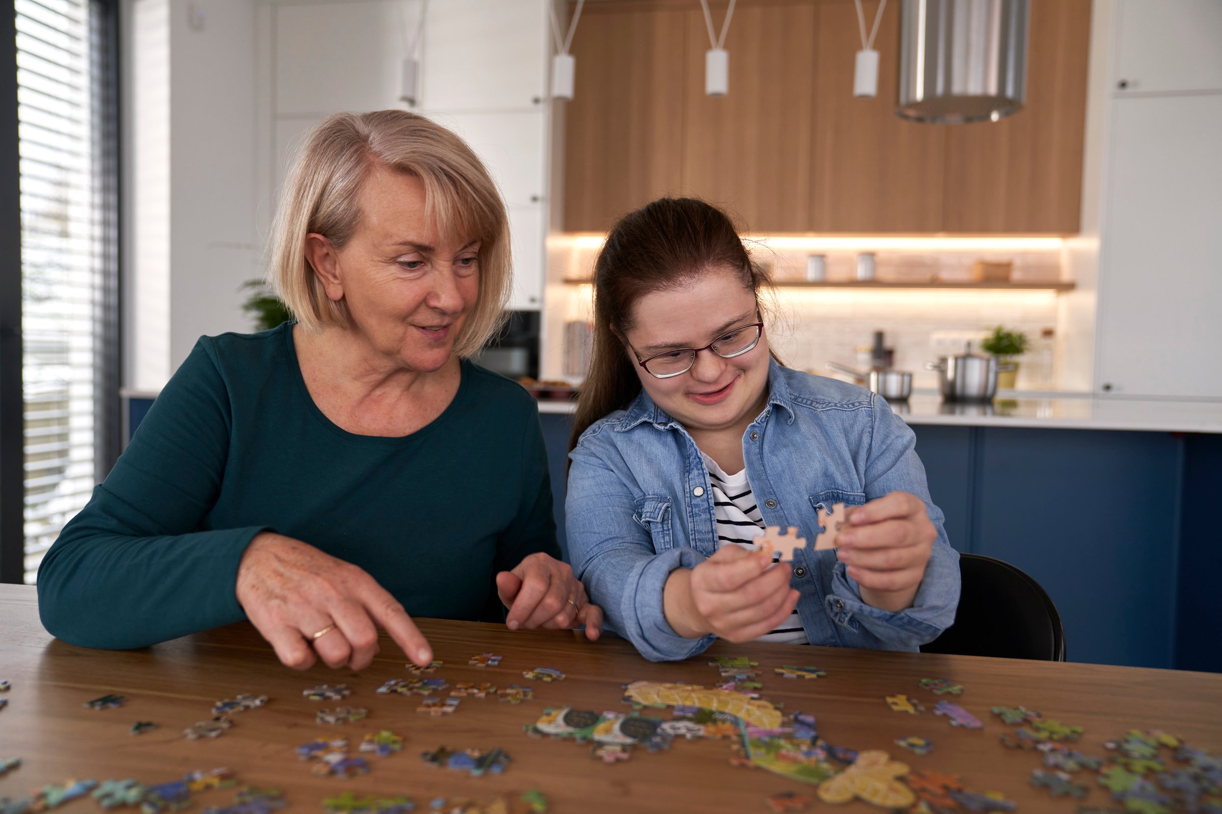 Focus down syndrome woman and her mother assembling puzzles at home