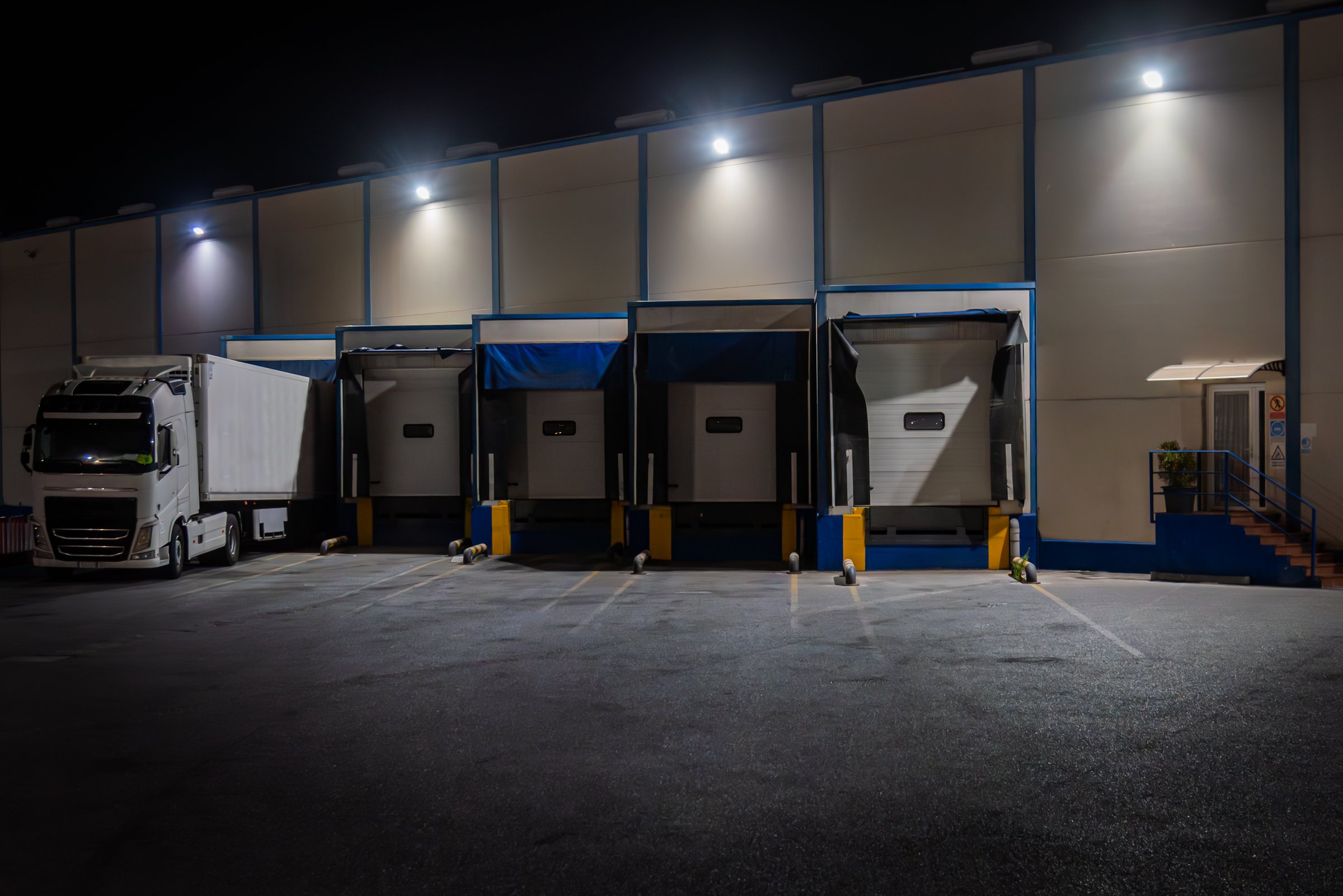 Loading docks of a fruit and vegetable warehouse with a refrigerated truck parked at night