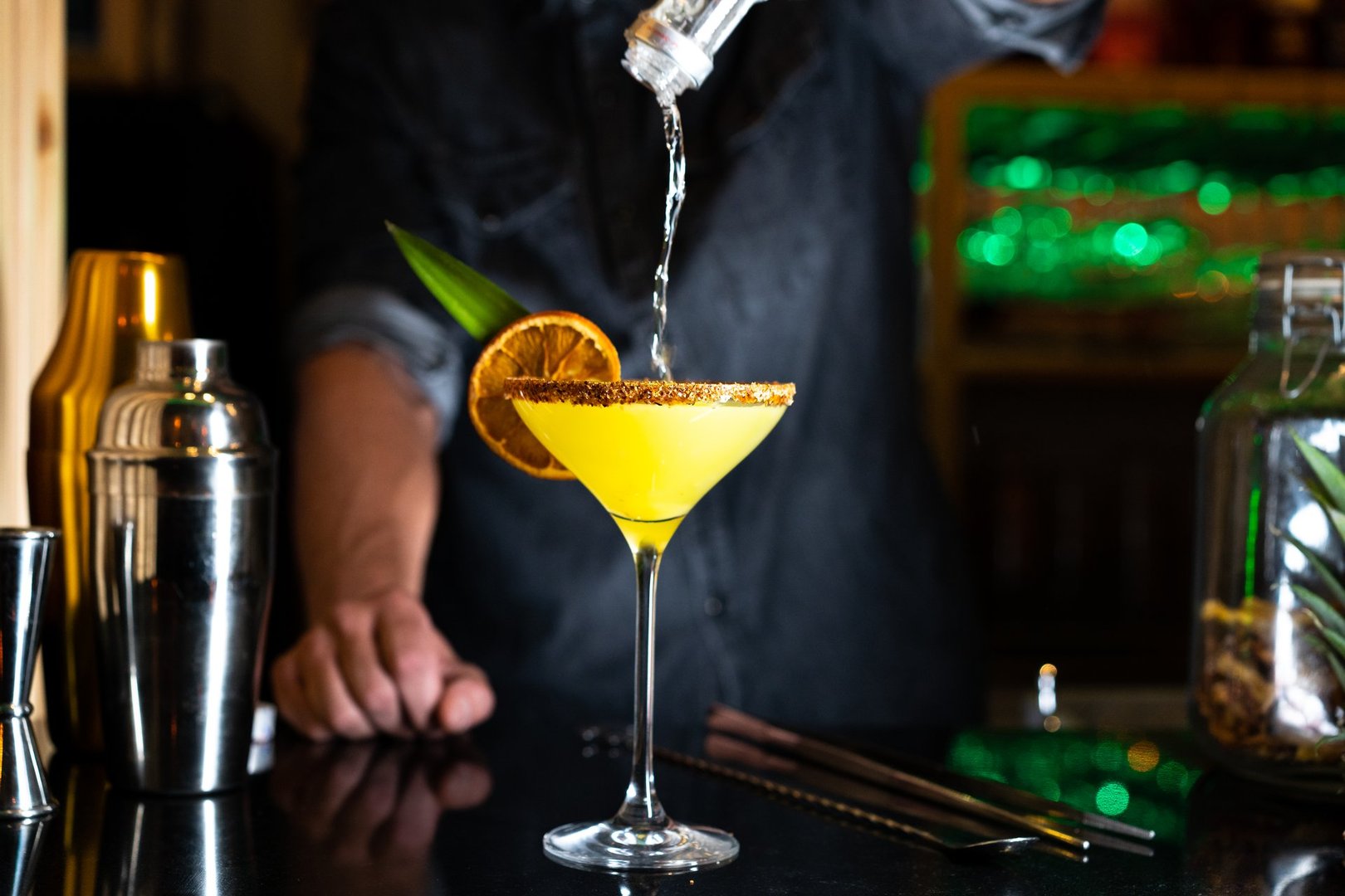 Bartender pouring alcohol on a cocktail in a night club bar. Close-up