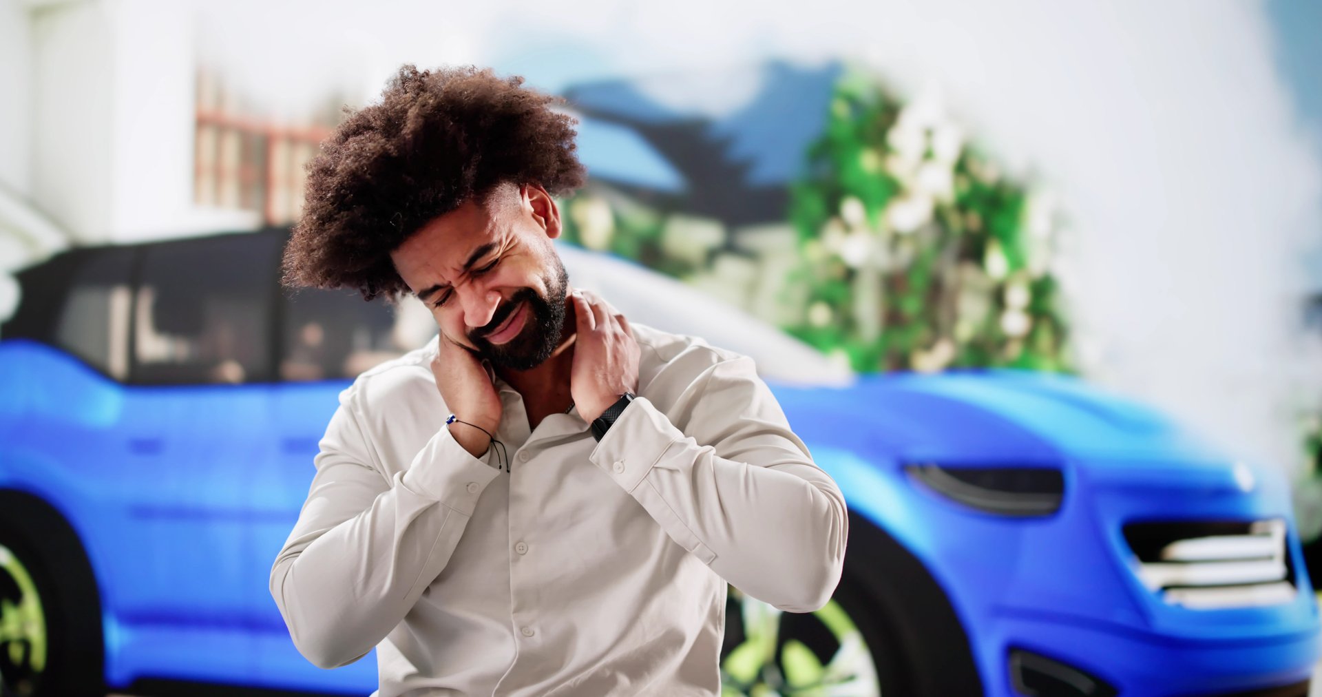 Young African American man in pain near smoking car accident.