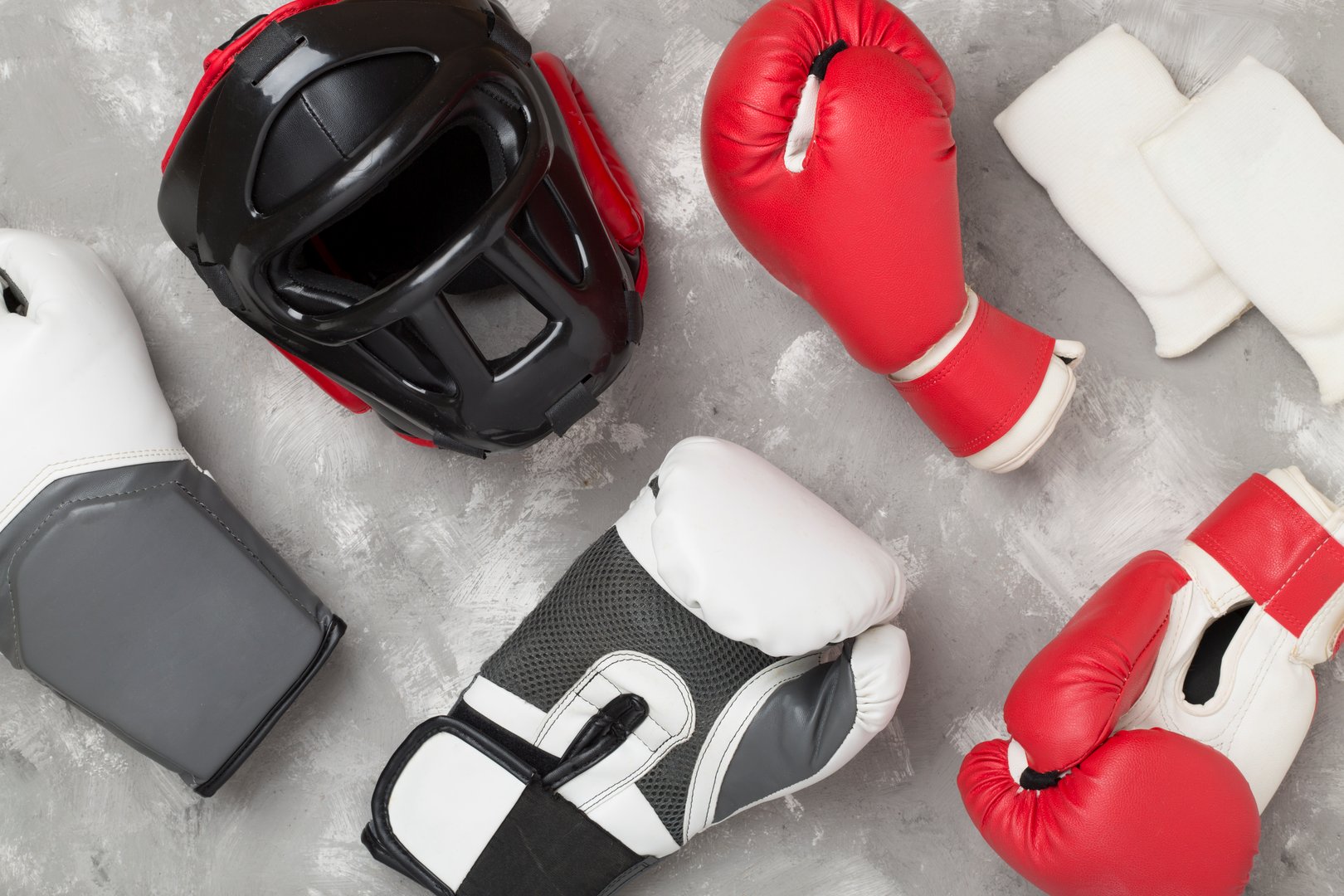 Boxing helmet and gloves on wooden background, top view.
