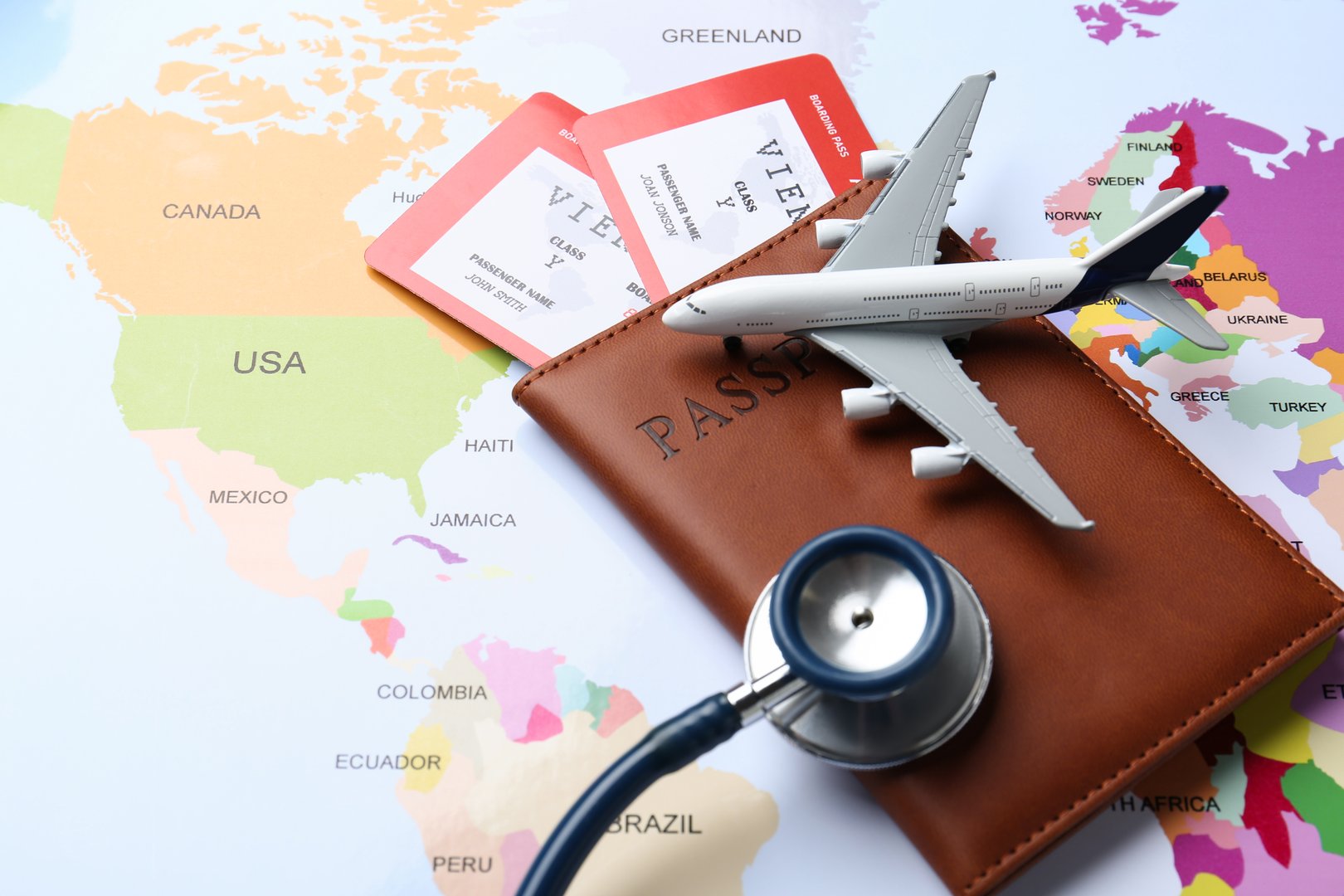 Medical tourism. Passport with tickets, stethoscope and airplane model on world map, closeup