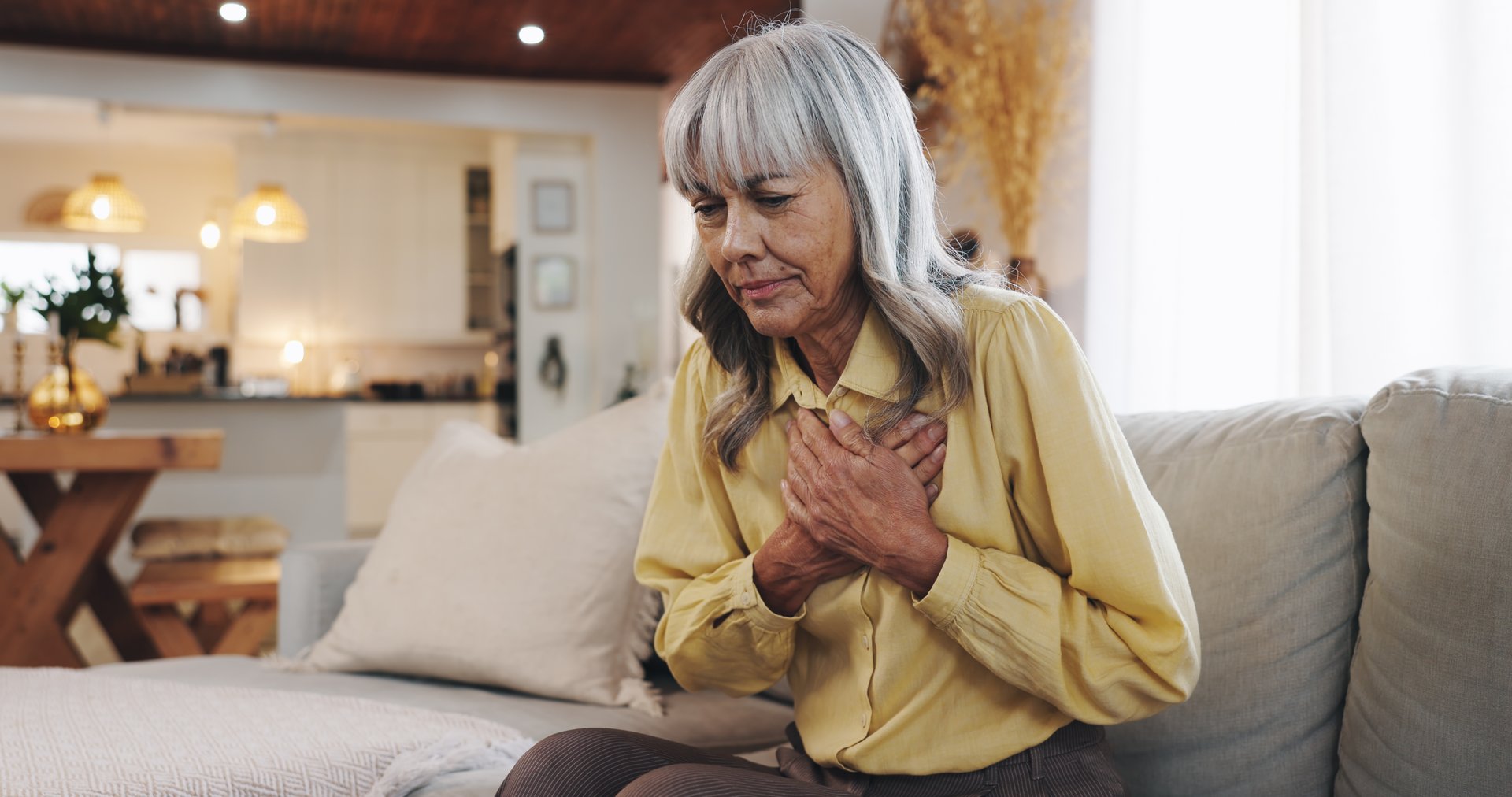 Heart attack, chest pain and sick with old woman on sofa for hypertension, medical emergency and stress. Anxiety, health risk and cardiac arrest with senior person at home for high blood pressure