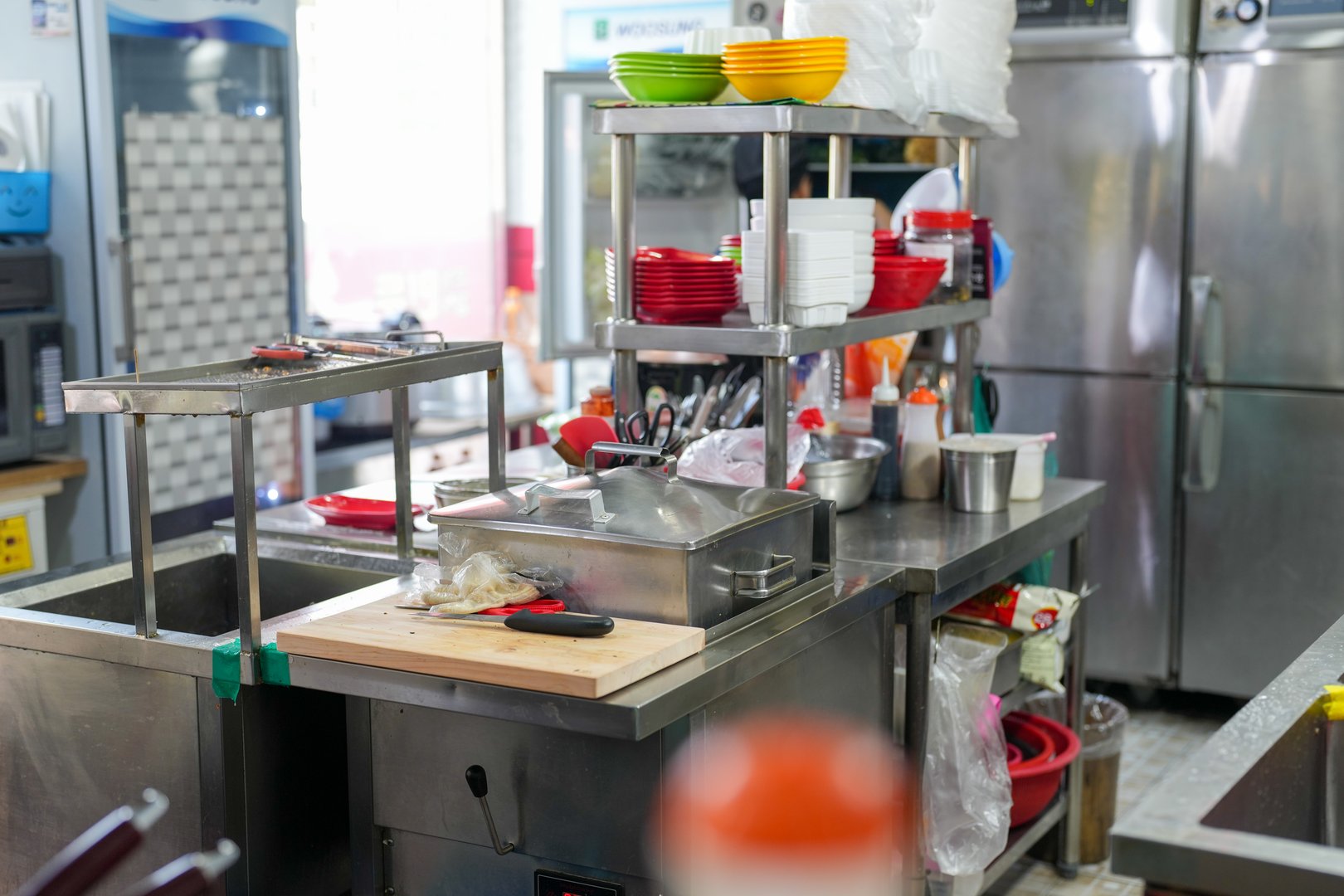 A kitchen with a counter top and a sink. There are many bowls and spoons on the counter