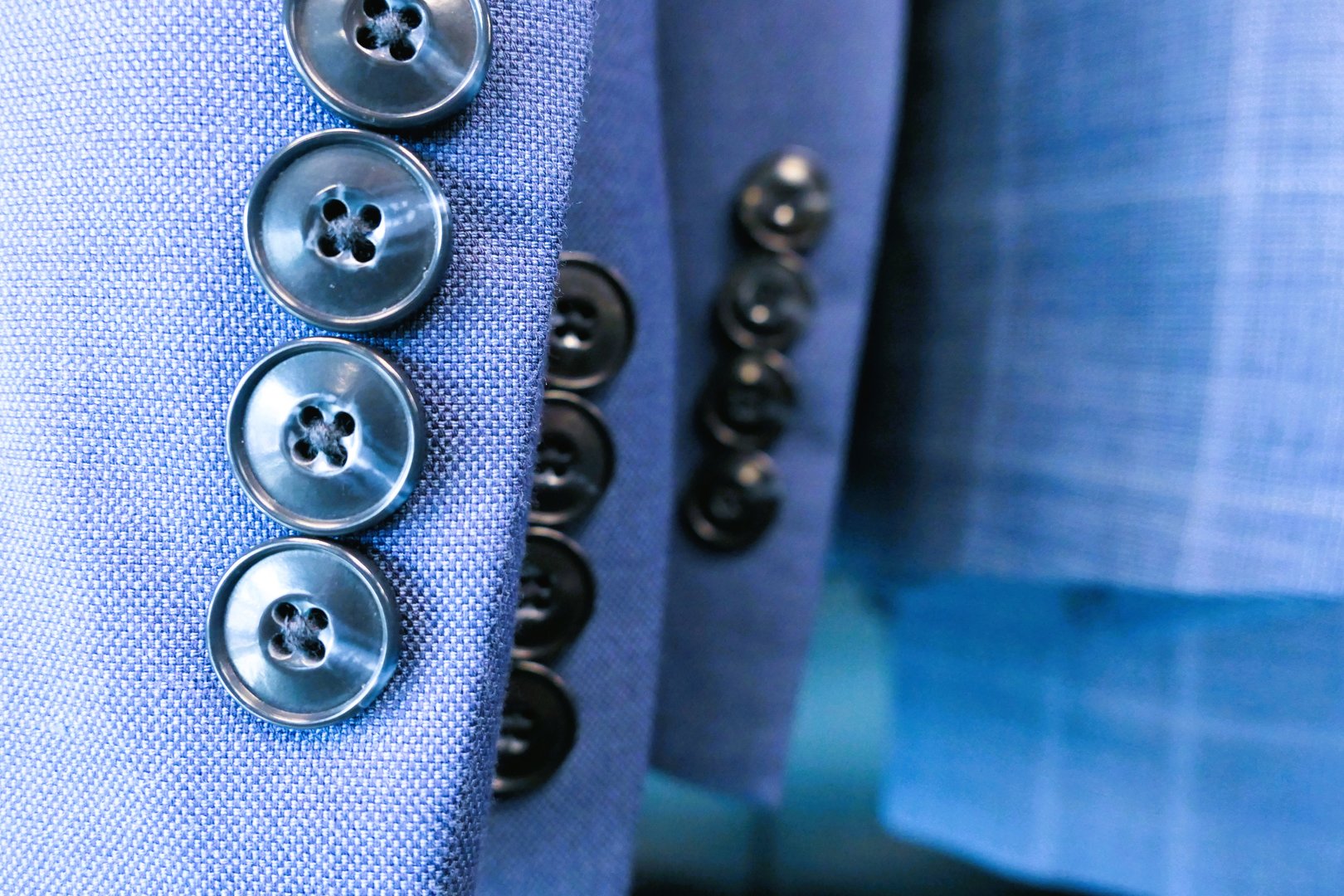 Close up of rack of bue dress jacket sleeves with buttons