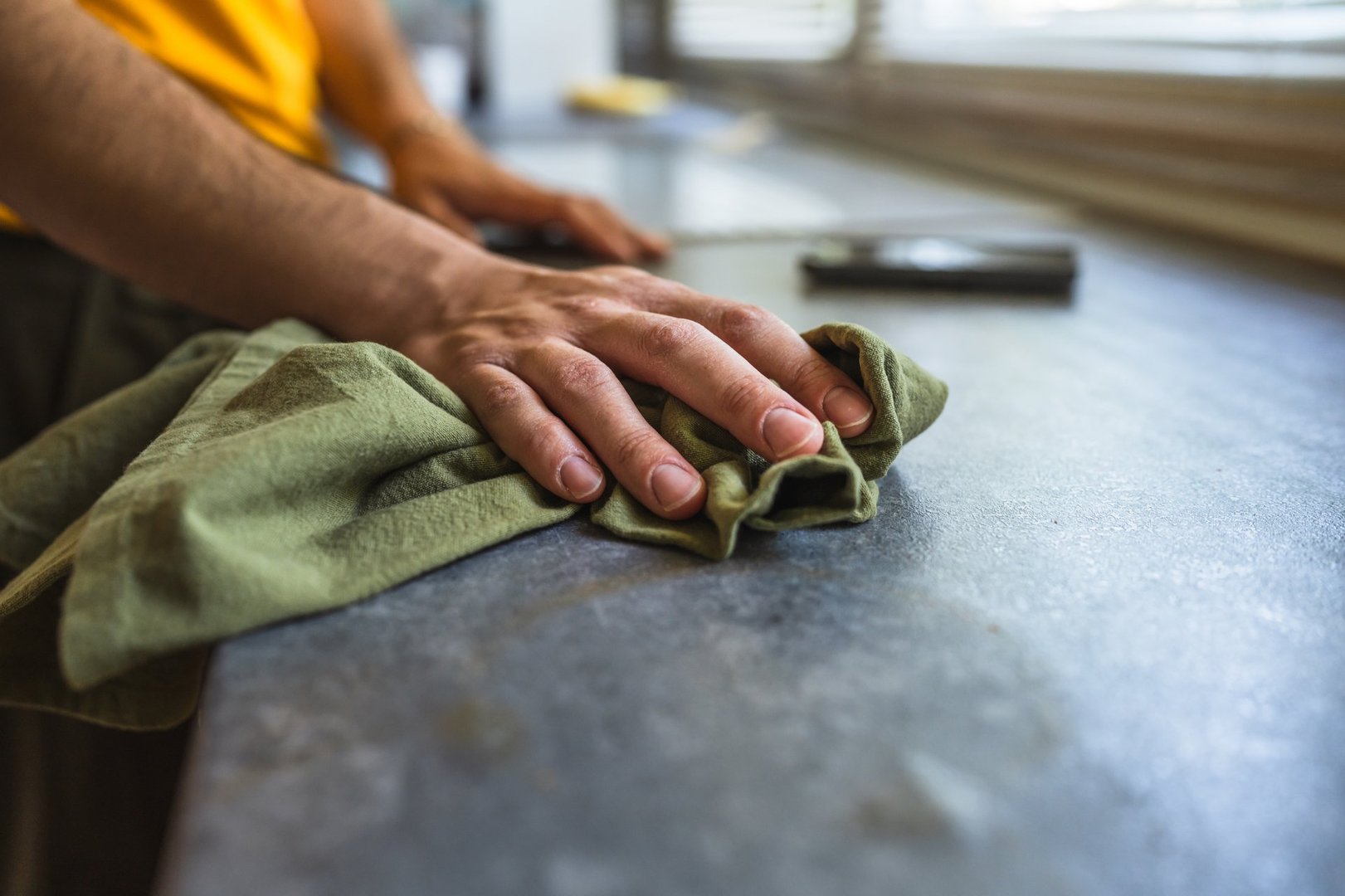 close up on male hand wiping and disinfecting a kitchen counter with a rag