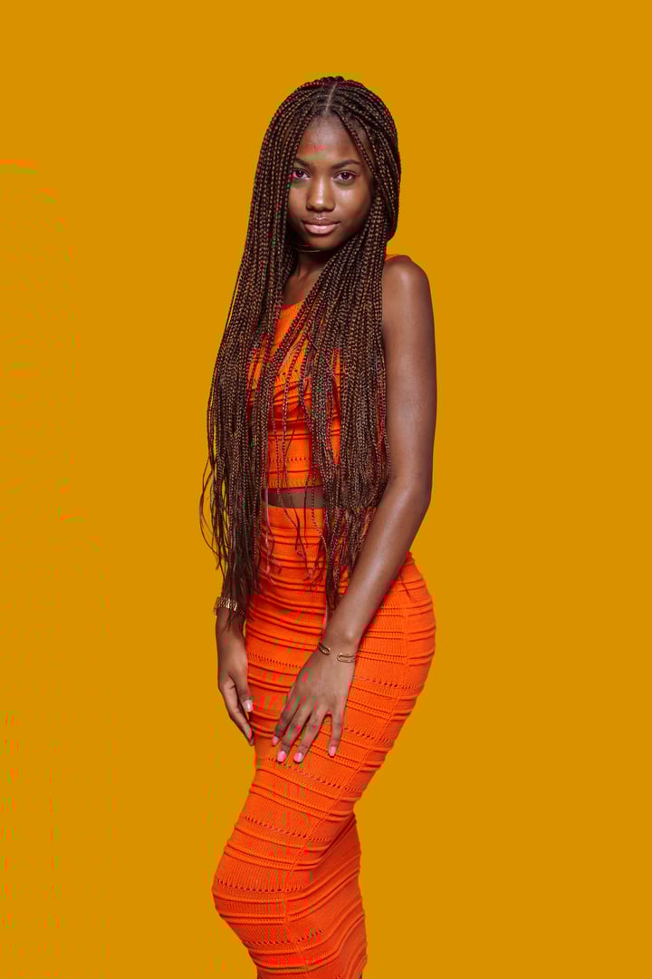 Fashion model posing with long braids on yellow background