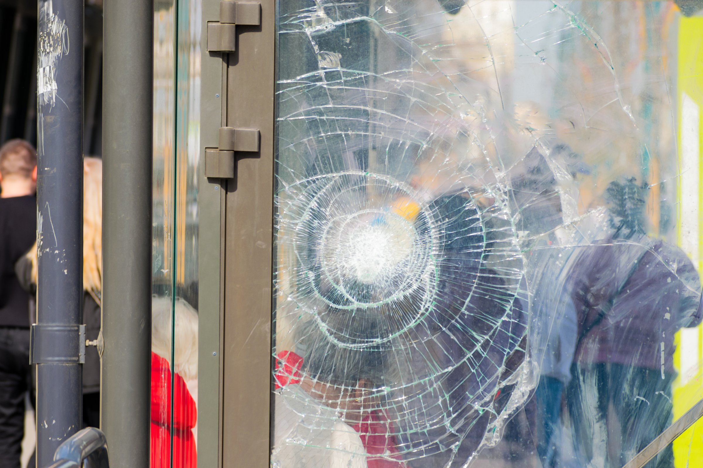 Broken glass at a public transport stop. anonymous people