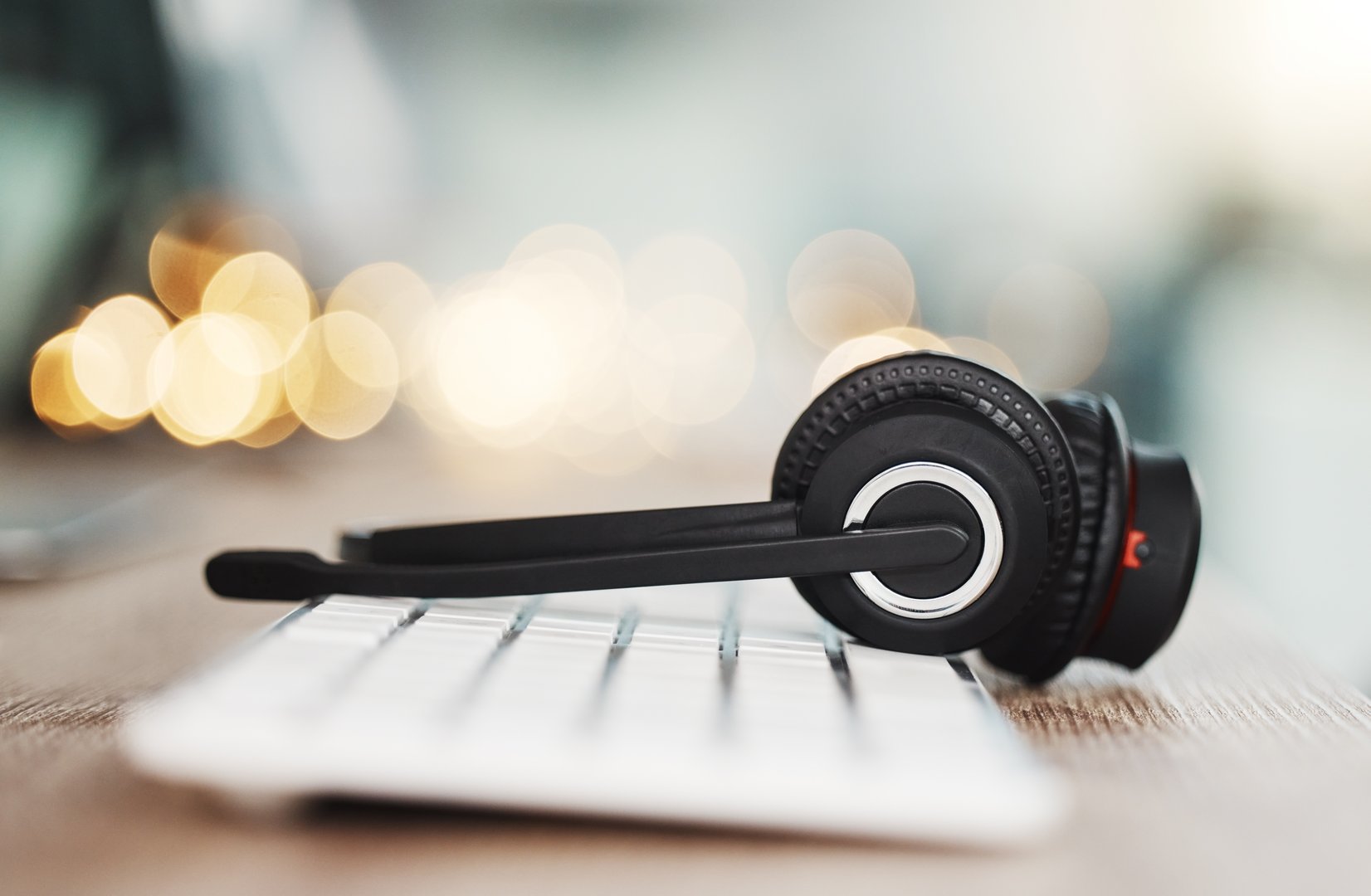 Call center headphones, computer keyboard and telemarketing background in office for contact us, video call and virtual online consulting. Zoom of customer support help desk, technology and connection