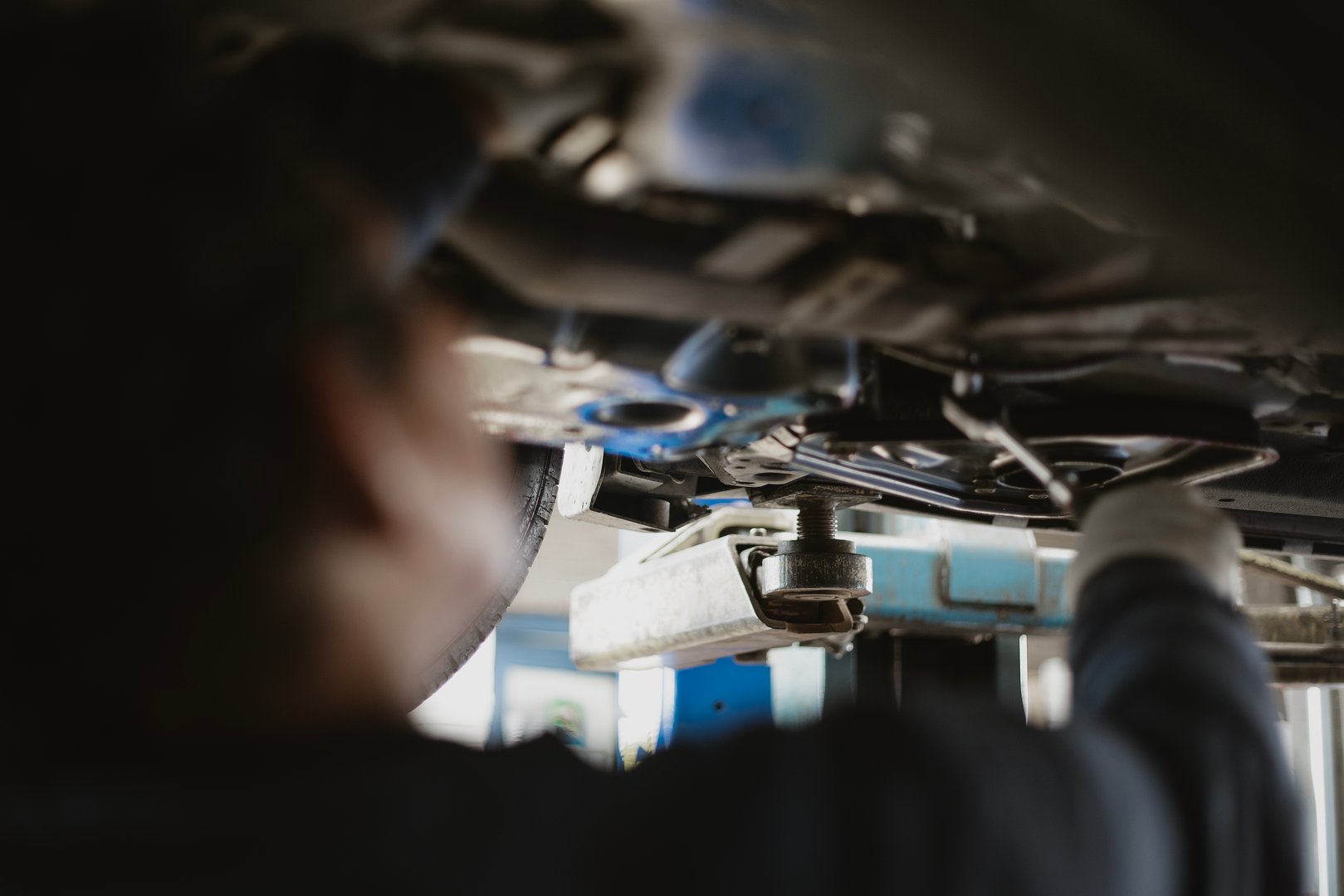 Mekaniker arbetar med reparation av fordon underifrån med verktyg synliga runt om