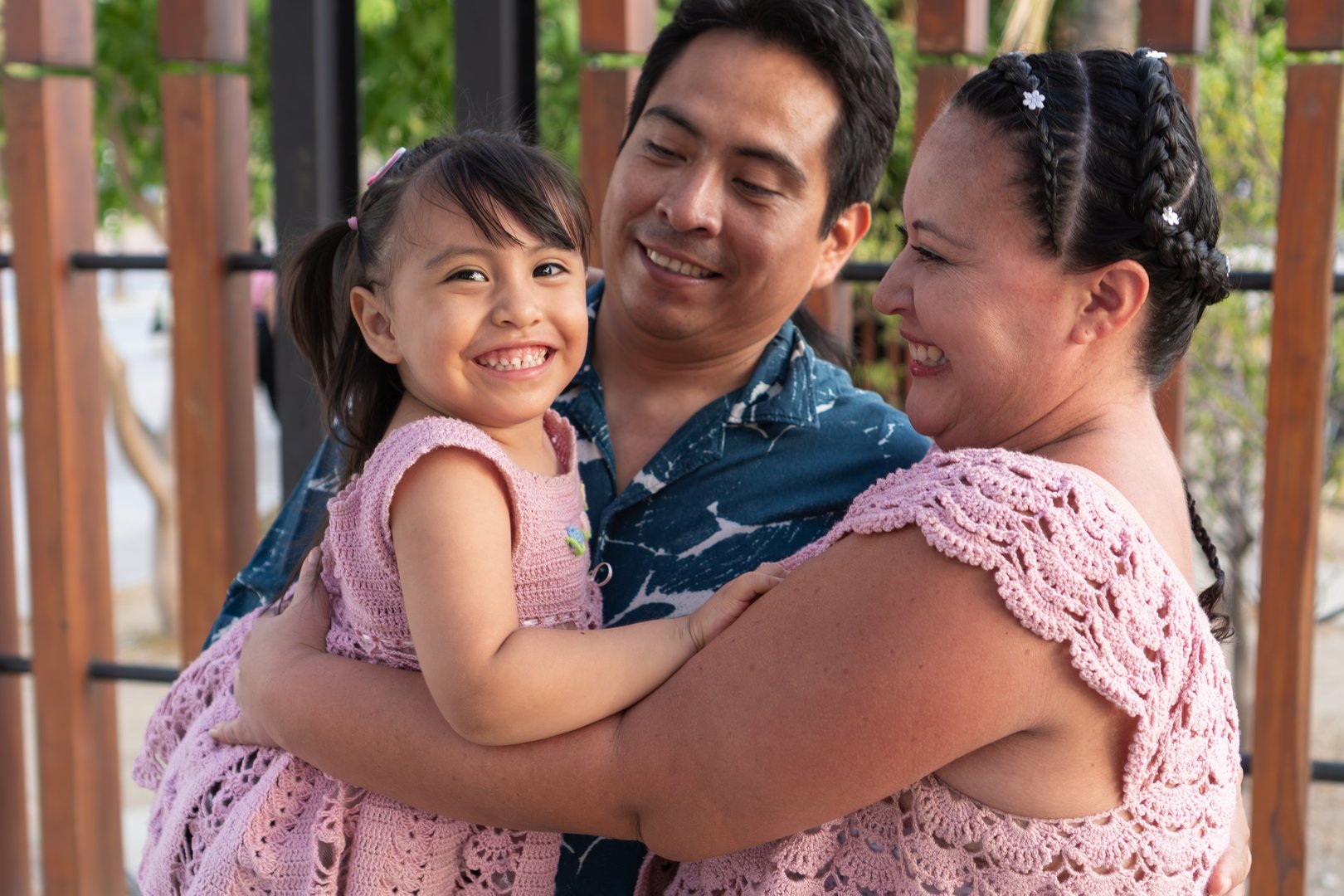 Happy hispanic family embracing each other and smiling outdoors