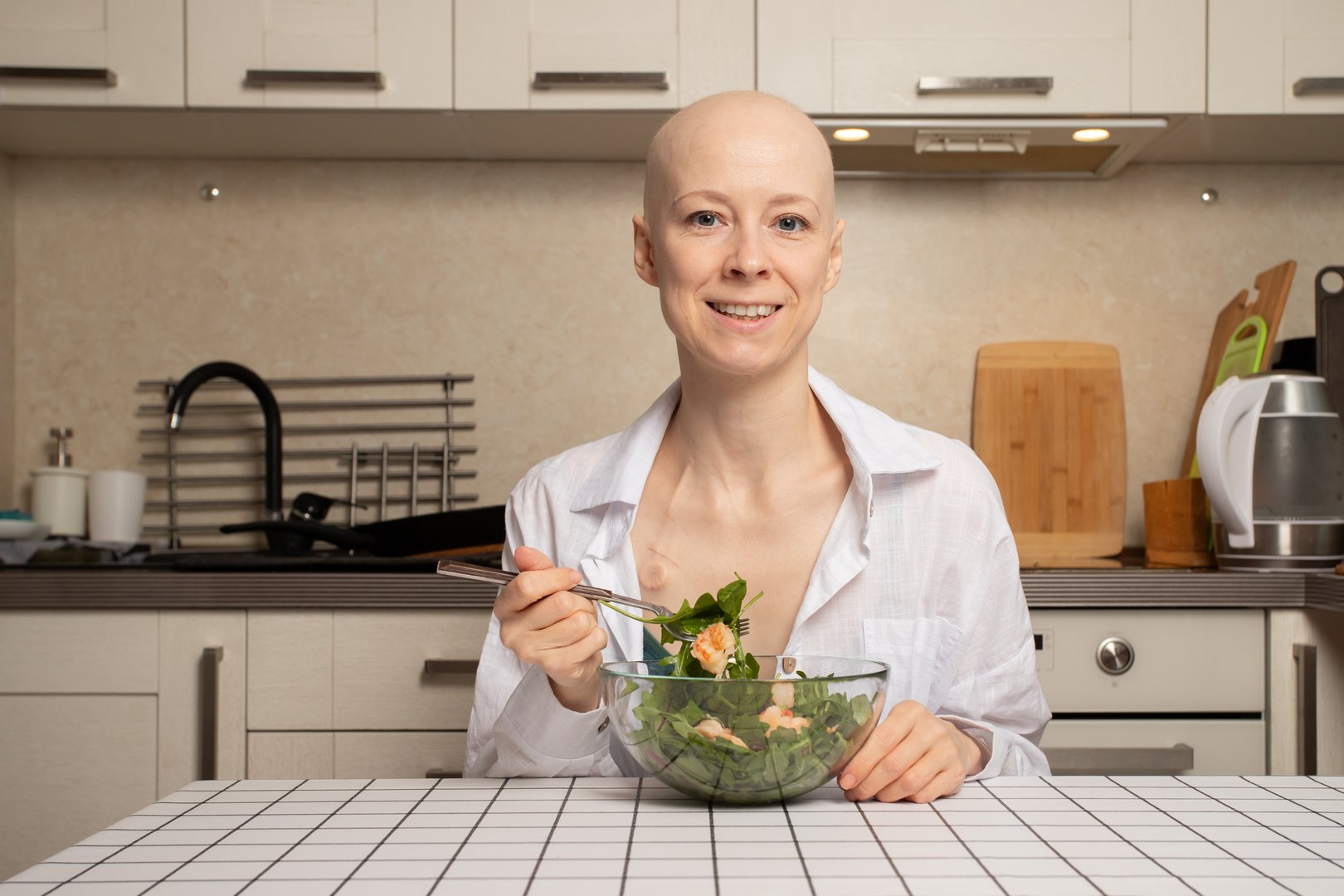 Bald woman in remission holding bowl of greens, chemotherapy patient focusing on healthy eating and natural vitamins, cancer support and positive mindset