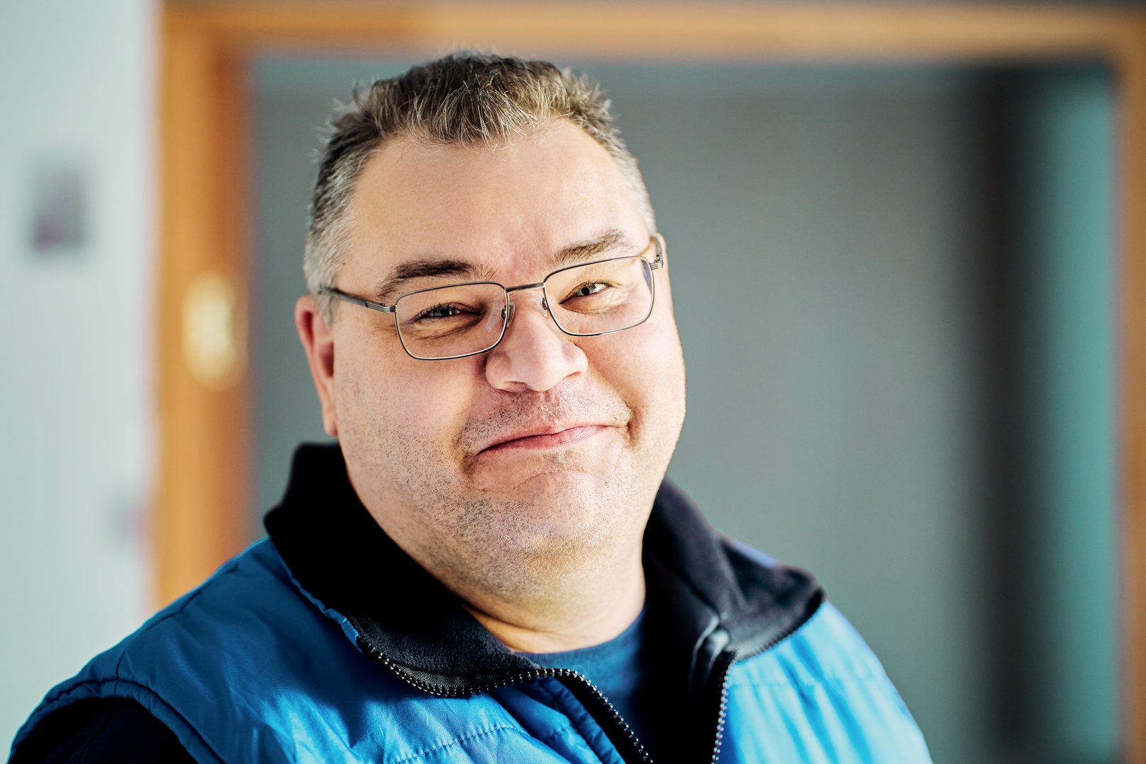 Face of large European man, 47 years old, wearing prescription glasses and smiling slyly.