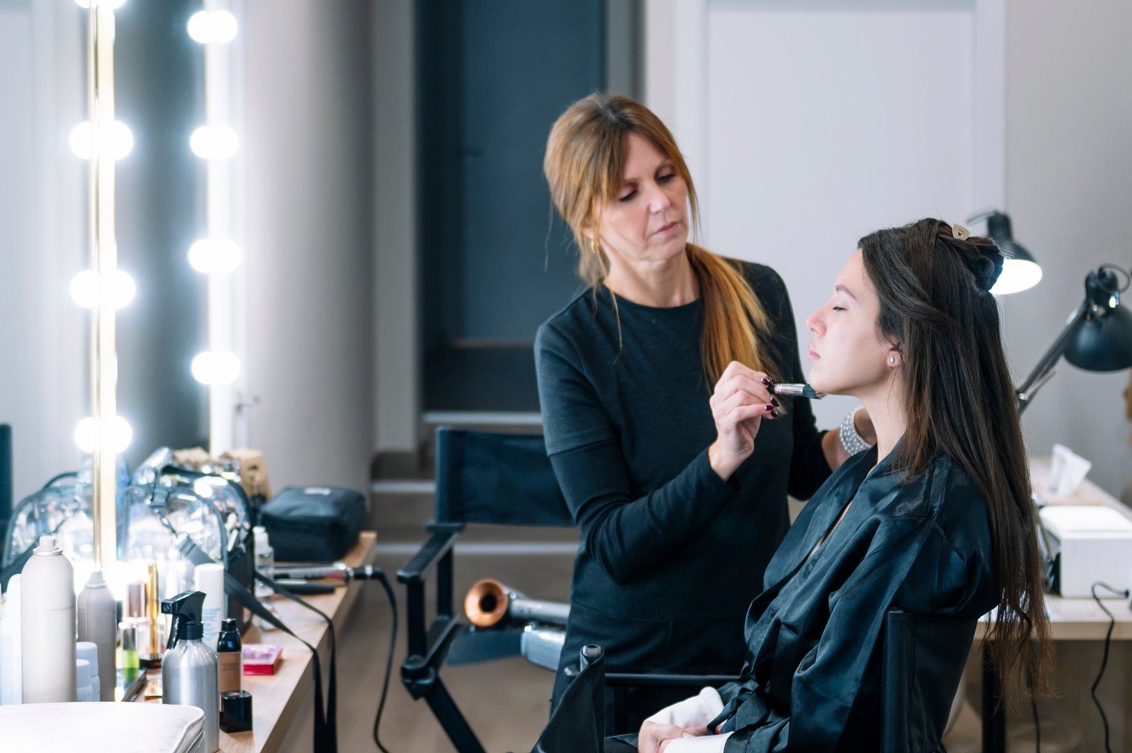 Professional makeup artist working on a client in a studio for beauty preparation