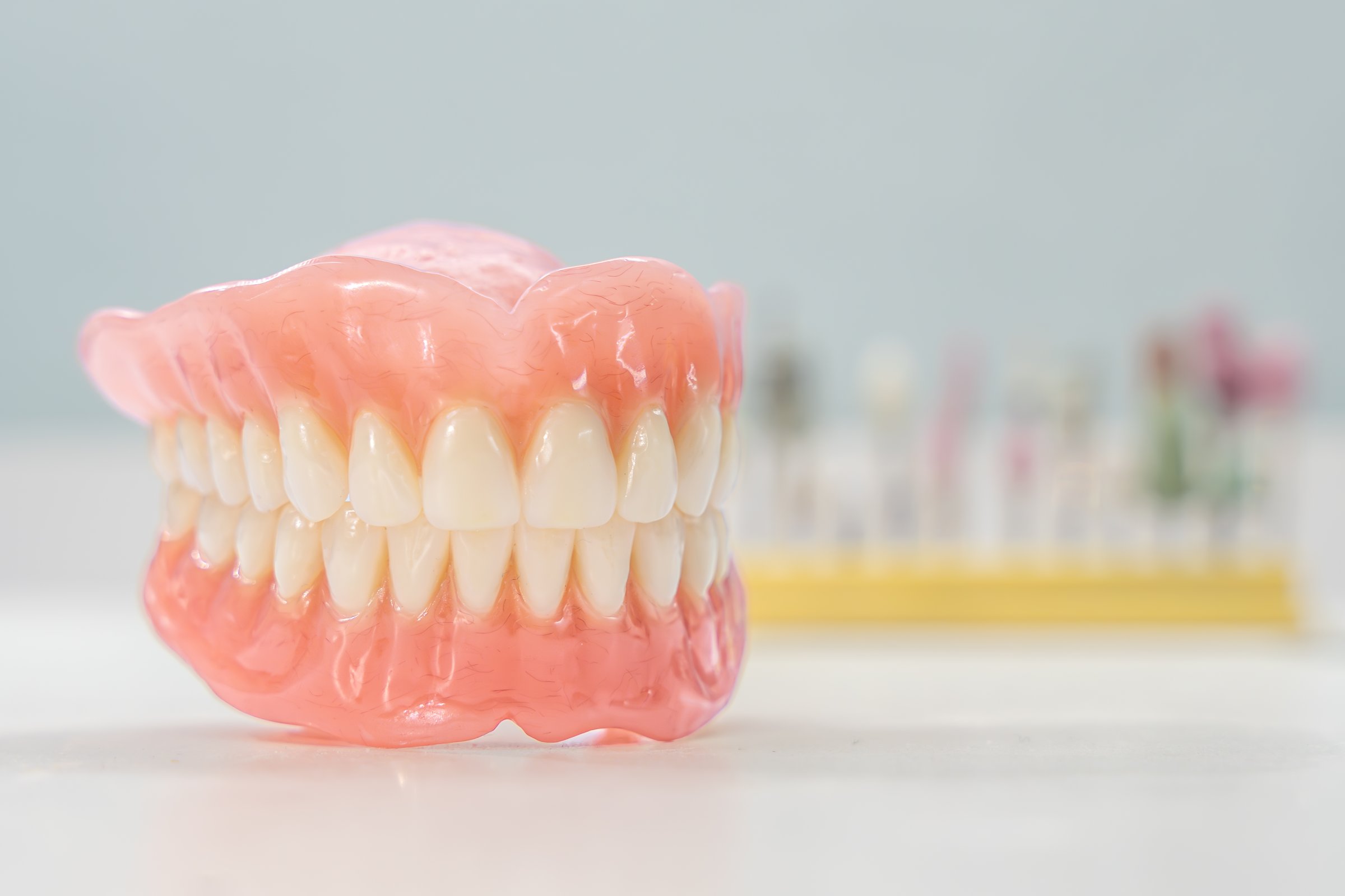 Close-up of a dental prosthetic model with artificial teeth and gums on a wooden surface. Ideal for dental care imagery
