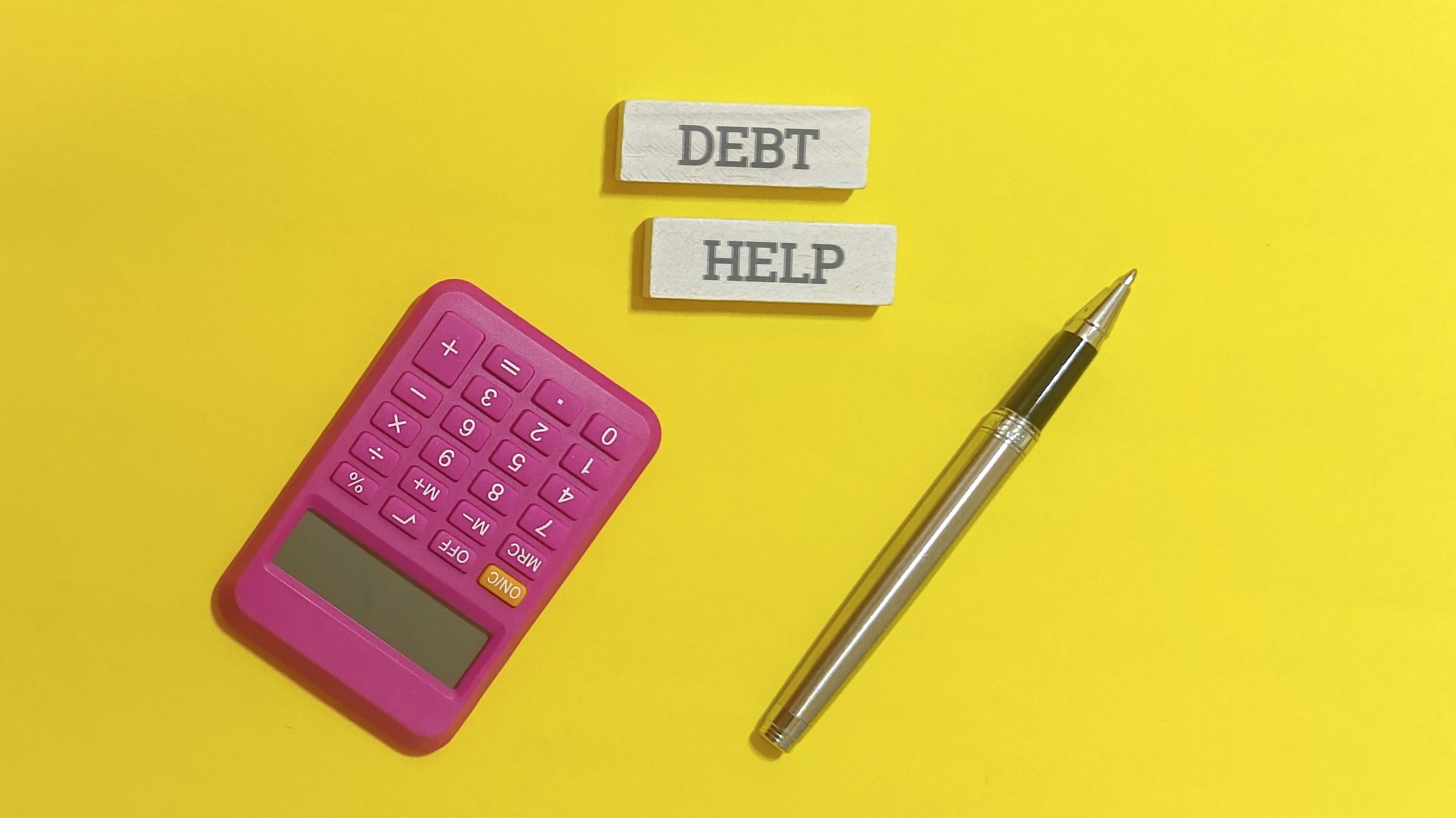 Debt help concept with calculator and pen on yellow background