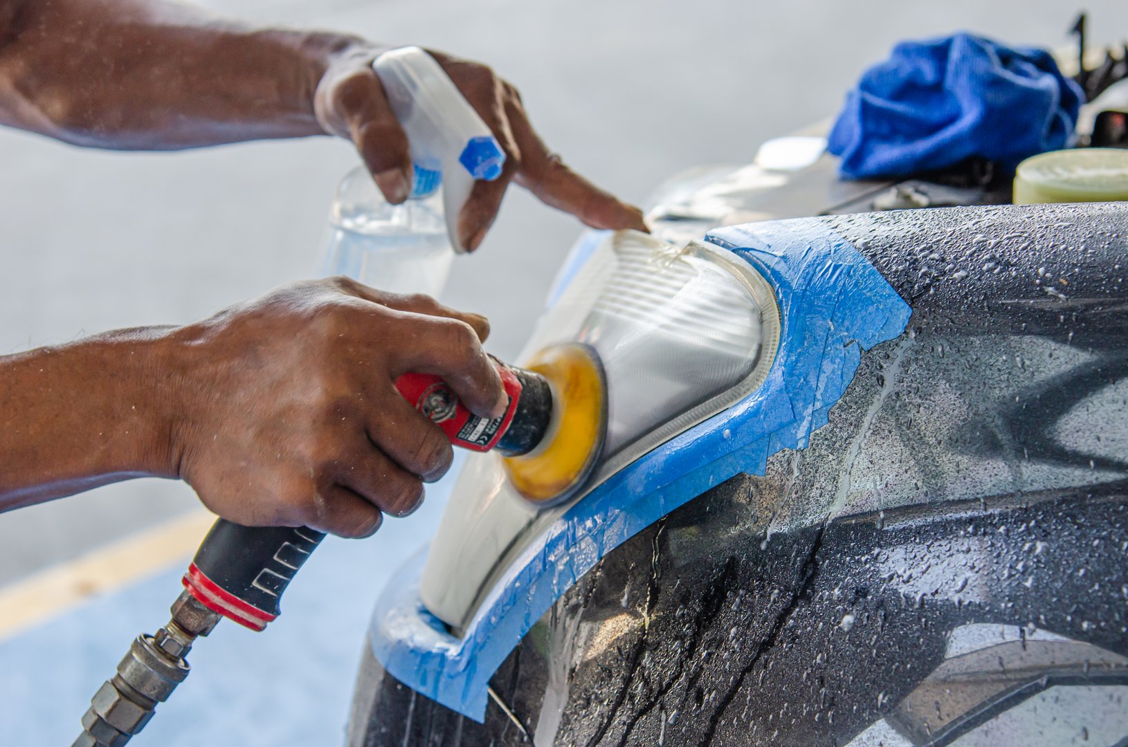 mechanic's hand is polishing the car's headlight.