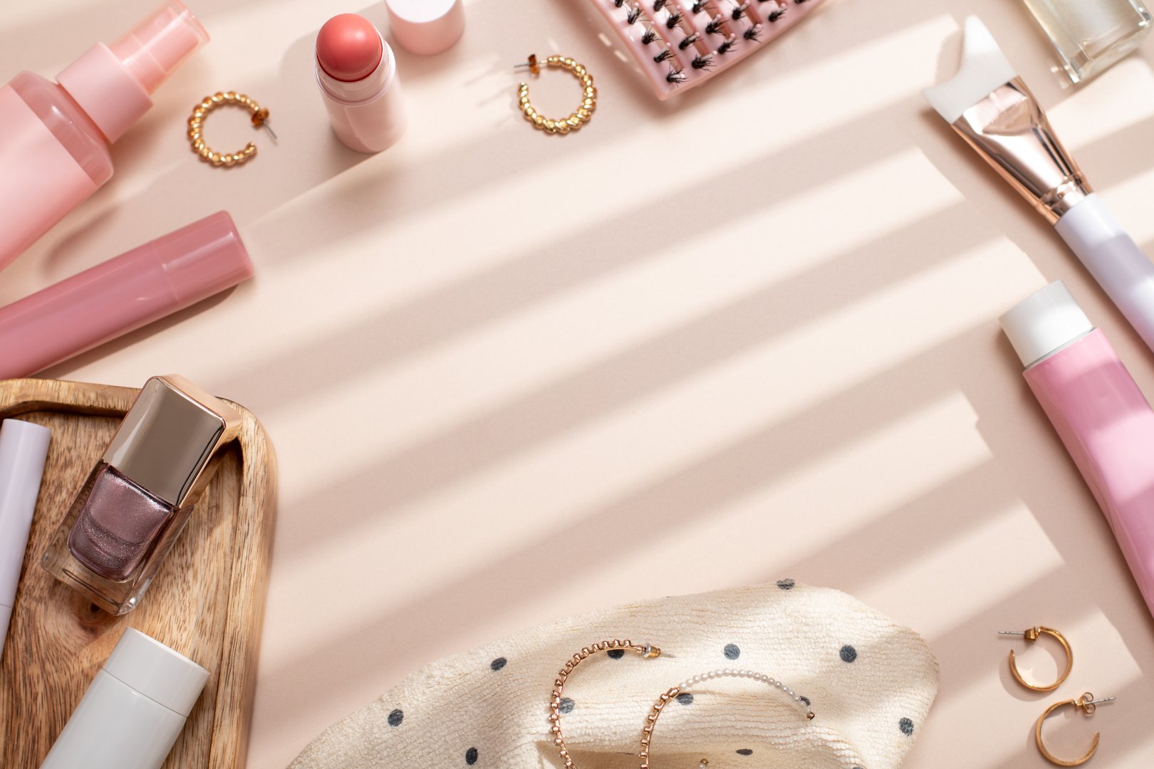 Beauty products frame background flat lay with skincare, haircare and makeup items on beige background filled with shadows,nostalgic retro aesthetic, top view, copy space