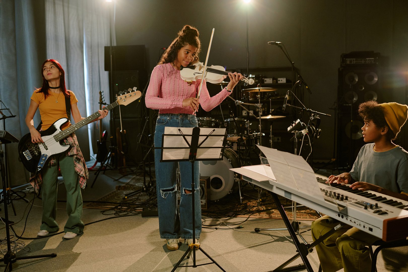 Wide shot of biracial teenagers having rehearsal at professional studio, they cooperating to create new album for fans