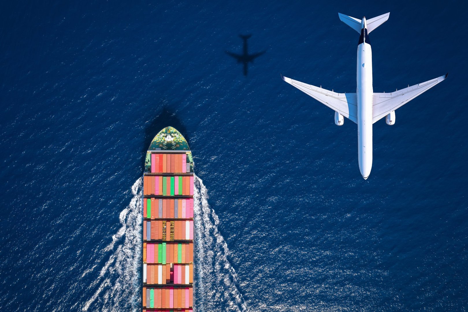 Aerial overhead view of a large container ship and airplane traveling over the ocean as a concept for transport and cargo
