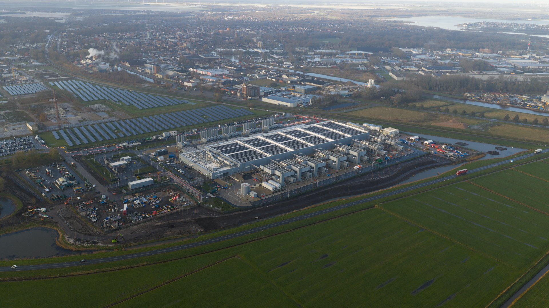 Dynamic aerial drone close-up of a newly built hyperscale data center in Winschoten, Netherlands. This facility integrates cutting-edge AI infrastructure running on sustainable and renewable energy sources, showcasing the future of green technology.