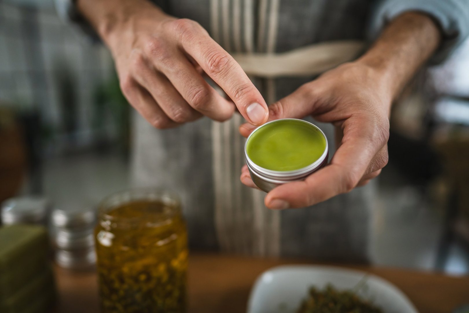 close up of man hands in apron hold organic natural balm in workshop