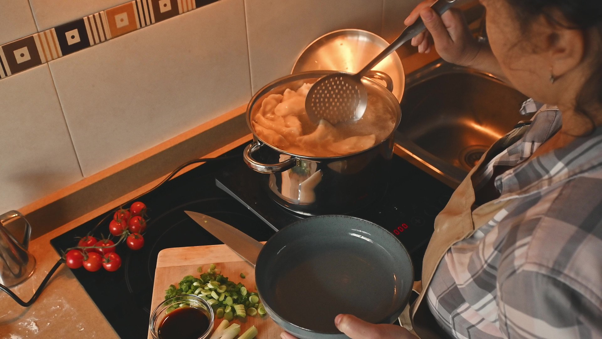 Overhead view of a woman preparing dumplings in a modern kitchen with fresh ingredients and a steaming pot, creating a rustic and inviting atmosphere.