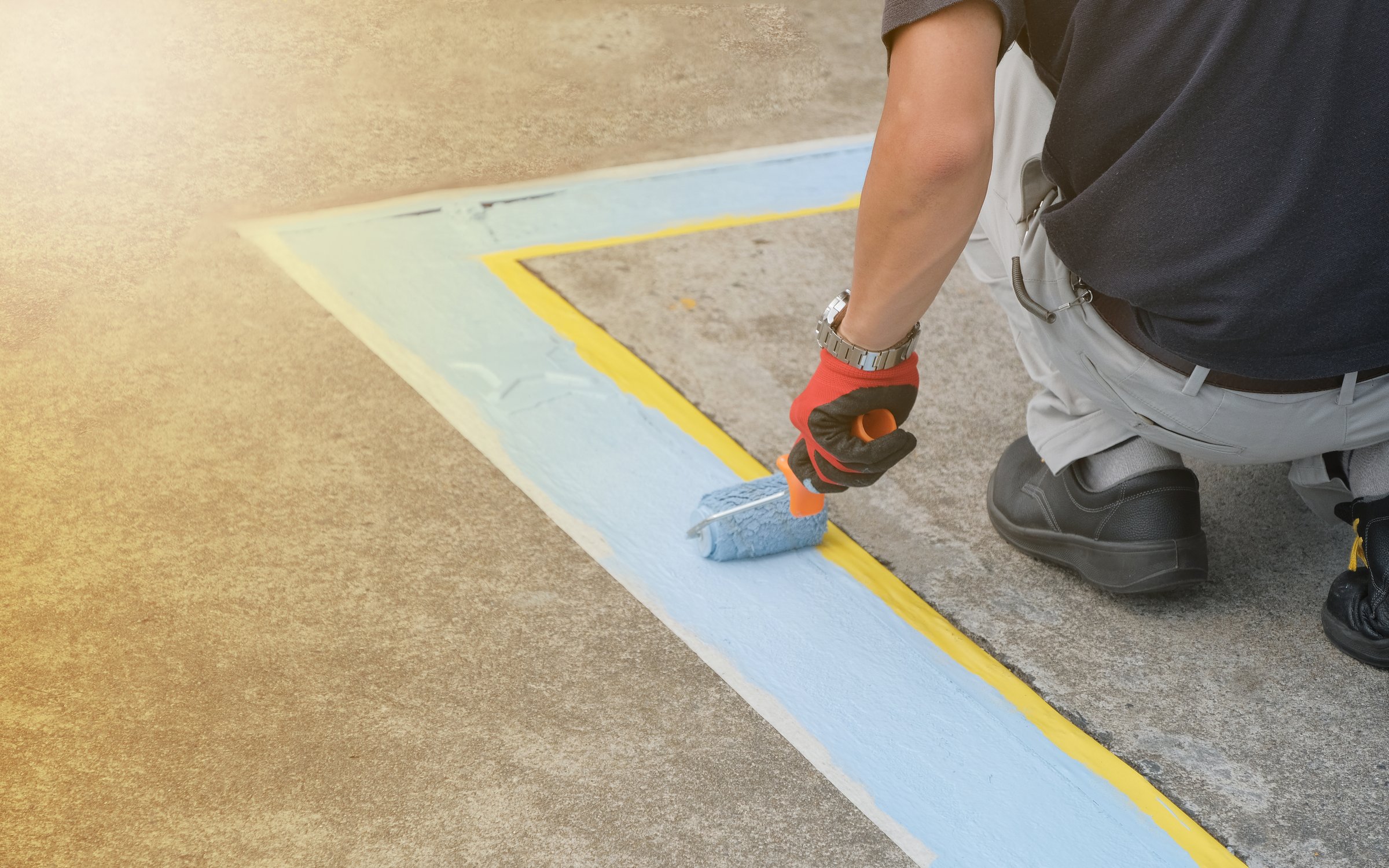 A painter painting parking lots blue lines striping in a car park