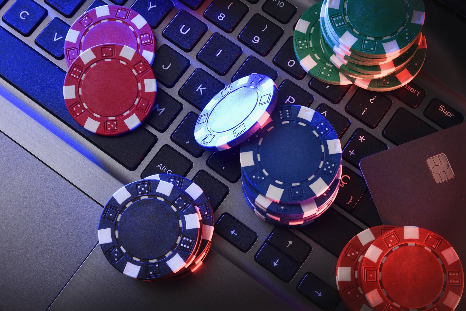 Online game betting concept with chips on laptop keyboard and bank card. Top view.