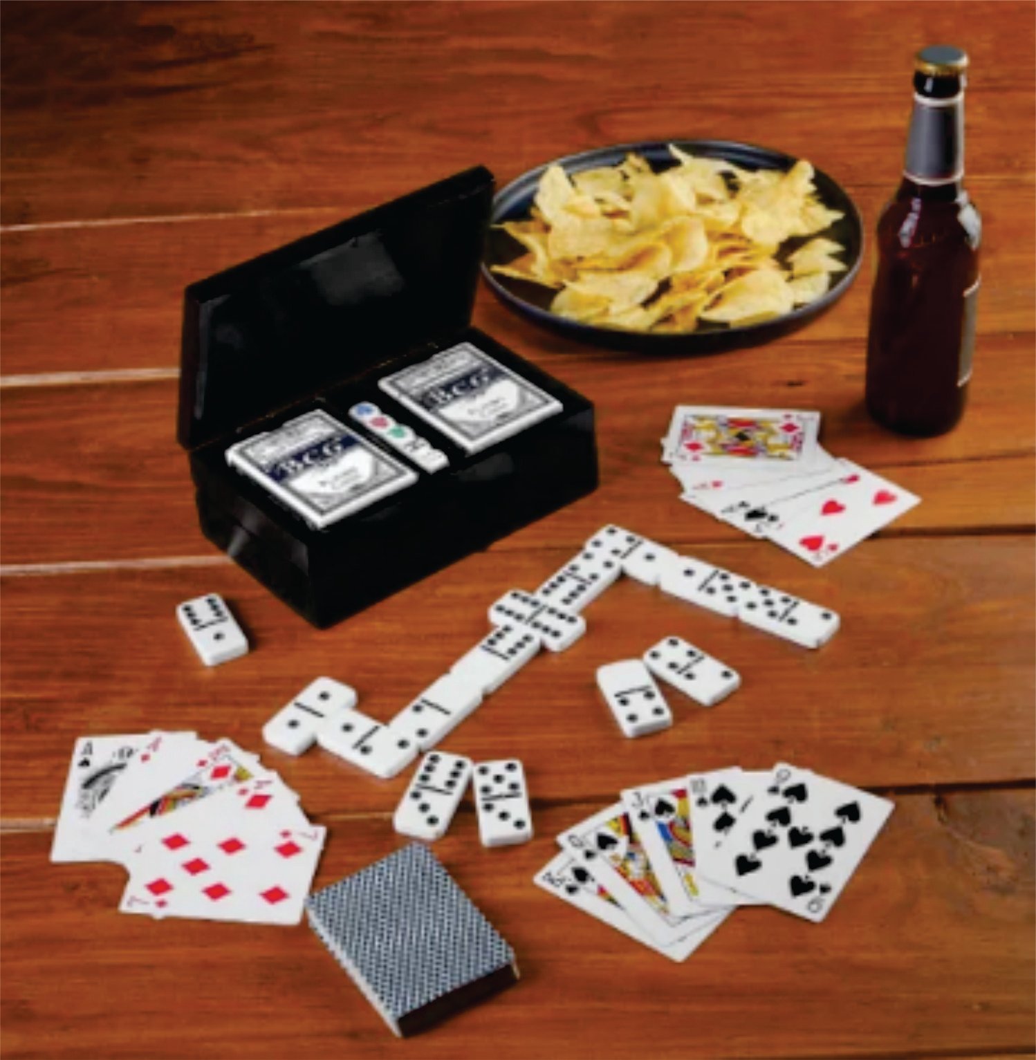 Playing cards, dominoes, a snack bowl with chips, and a beer bottle on a wooden table.