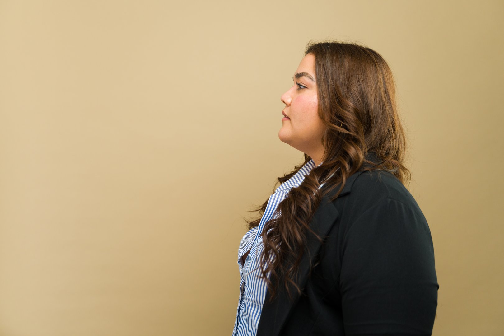 Profile view of an empowered plus-size woman in formal attire, posing in a studio