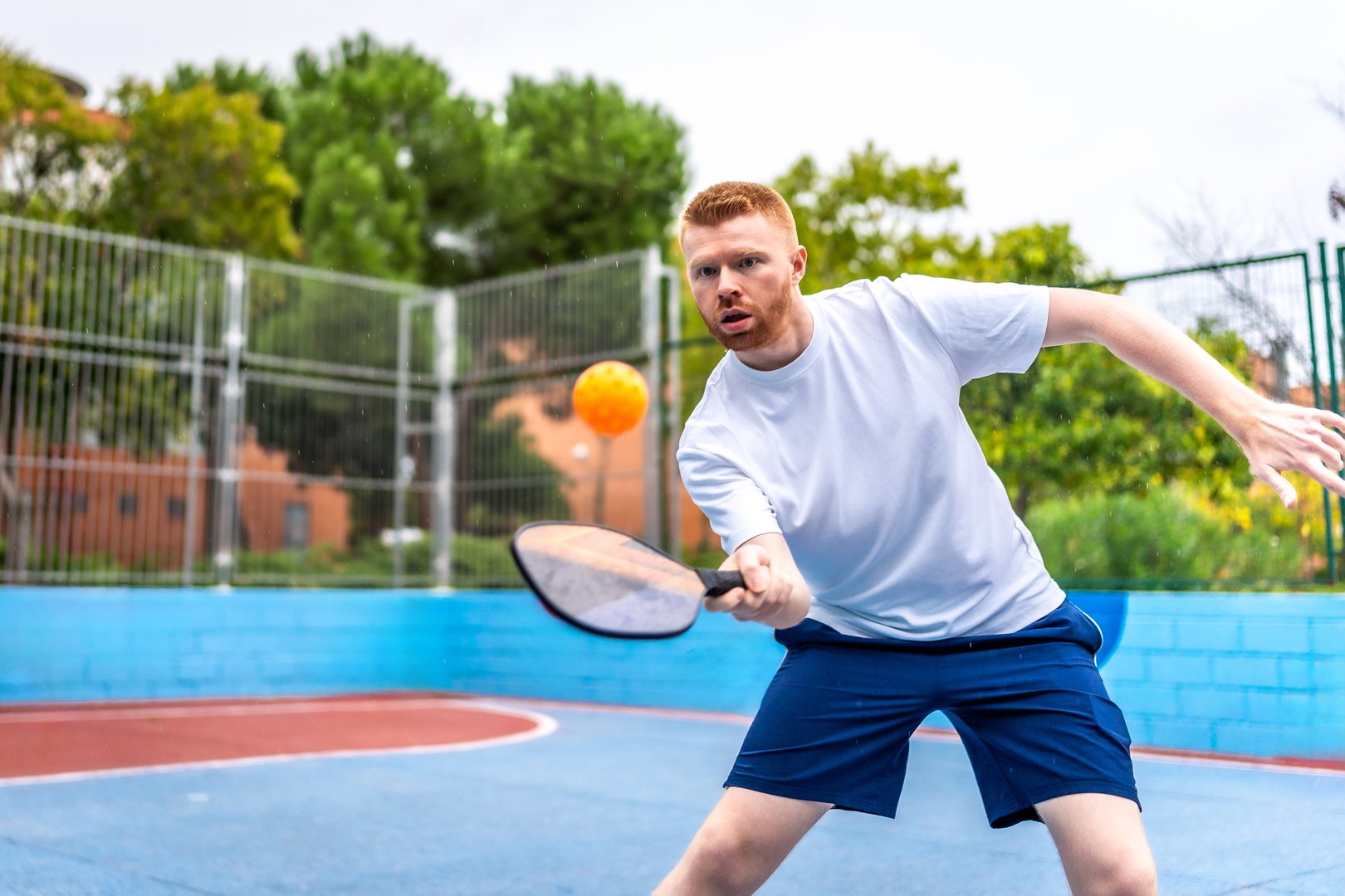 Energetic sportive young caucasian man playing pickelball in a colorful outdoor pitch