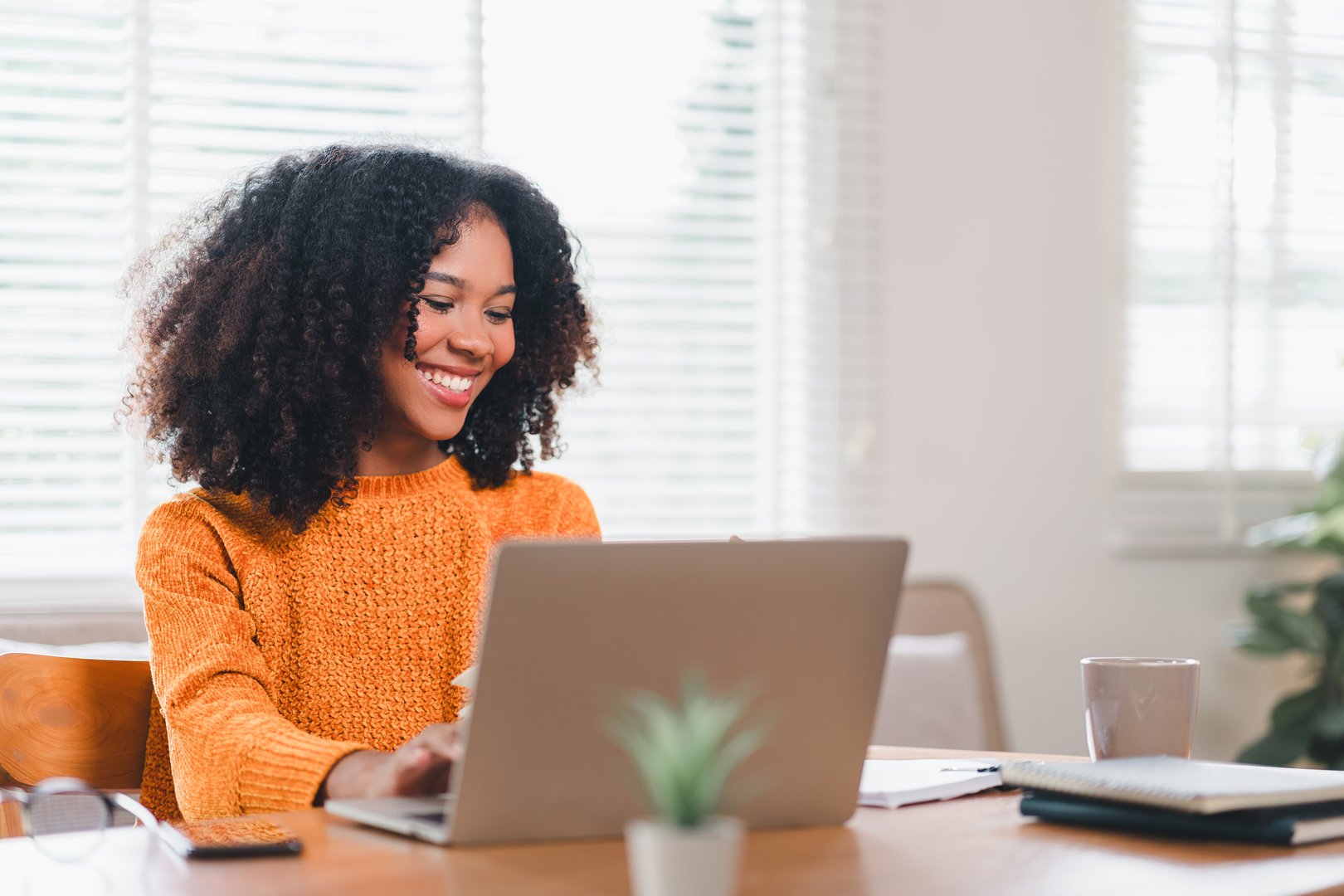 Happy African American woman wearing glasses working on laptop at home