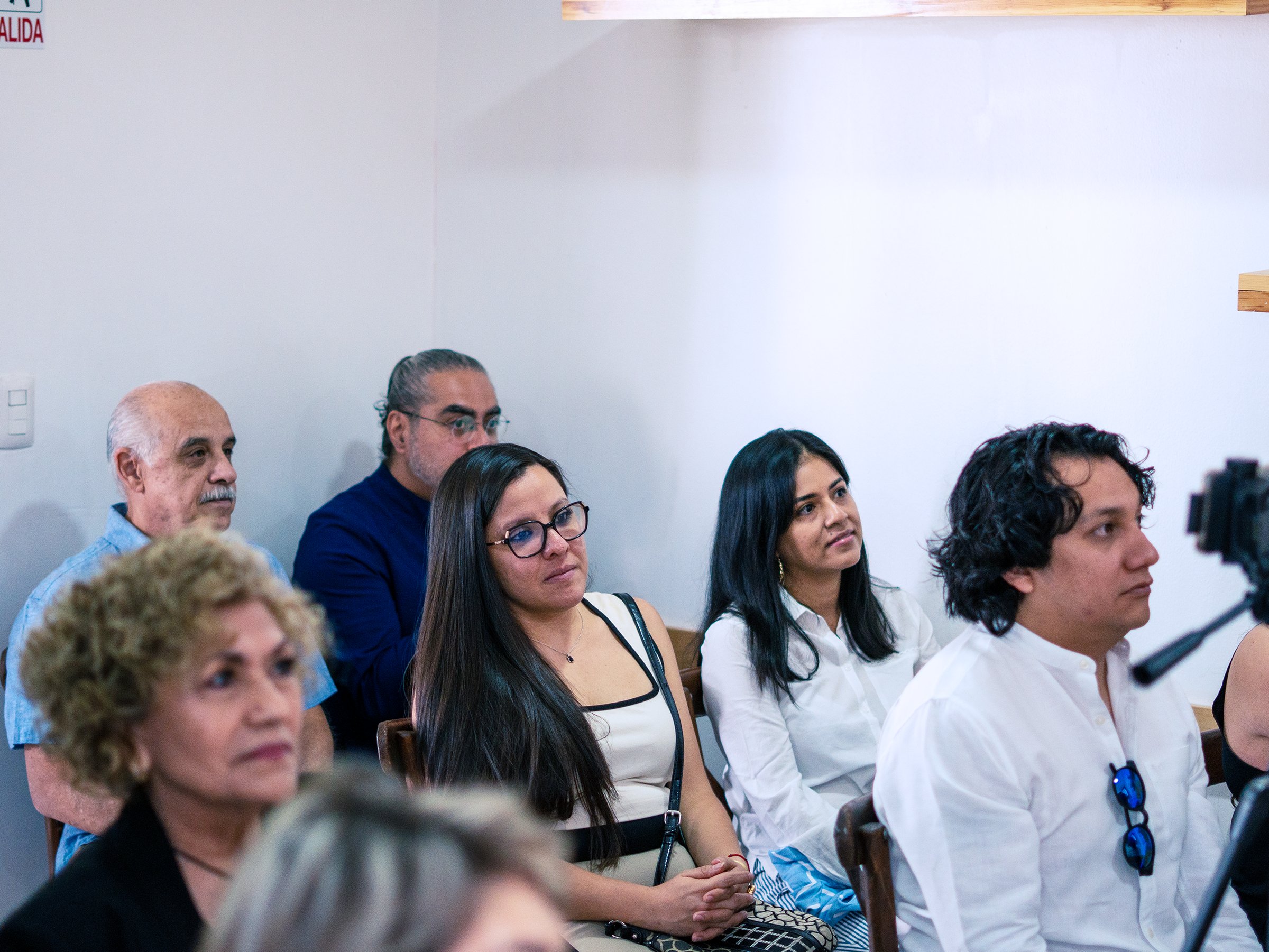 A group of people seated and listening attentively during a presentation or meeting.