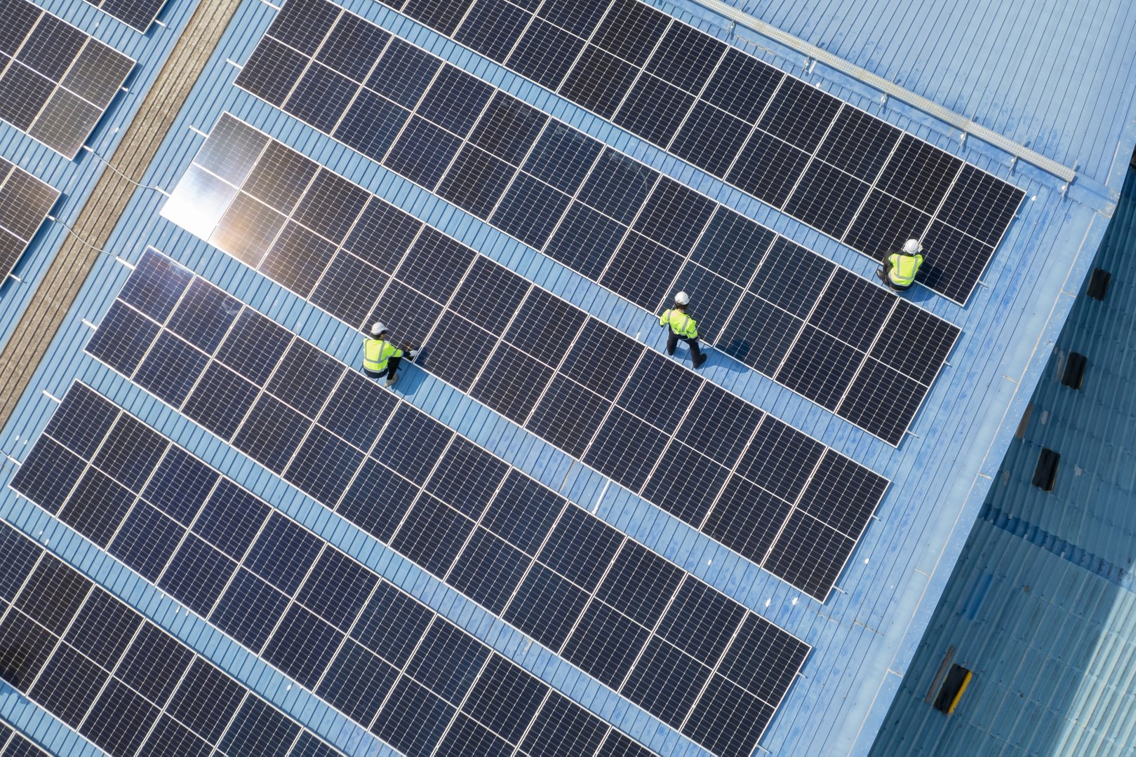 Arial view of engineers checking on solar panel on the factory rooftop