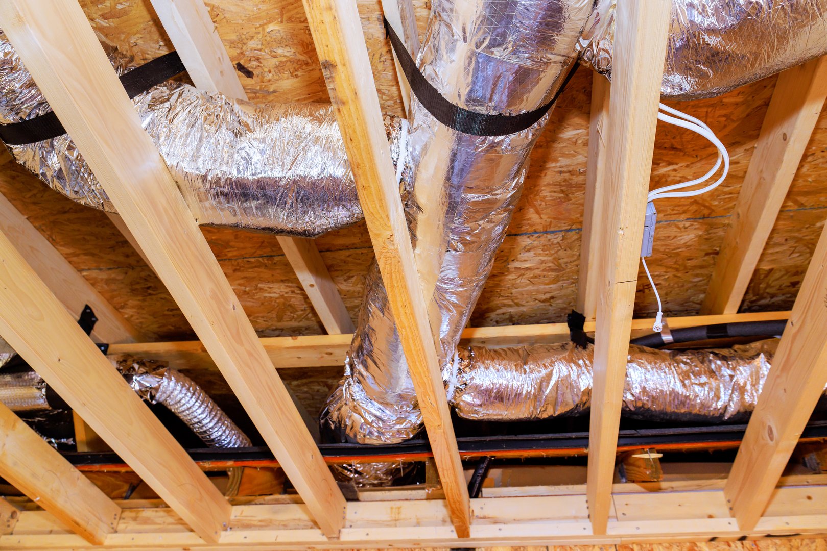 Ducts are being installed in ceiling structure of new building under construction, during ventilation work.