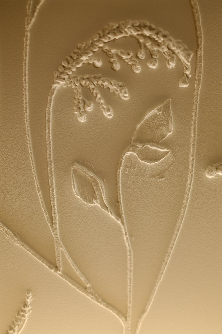 Embossed flowers and stems create a raised, neutral-toned decoration indoors.