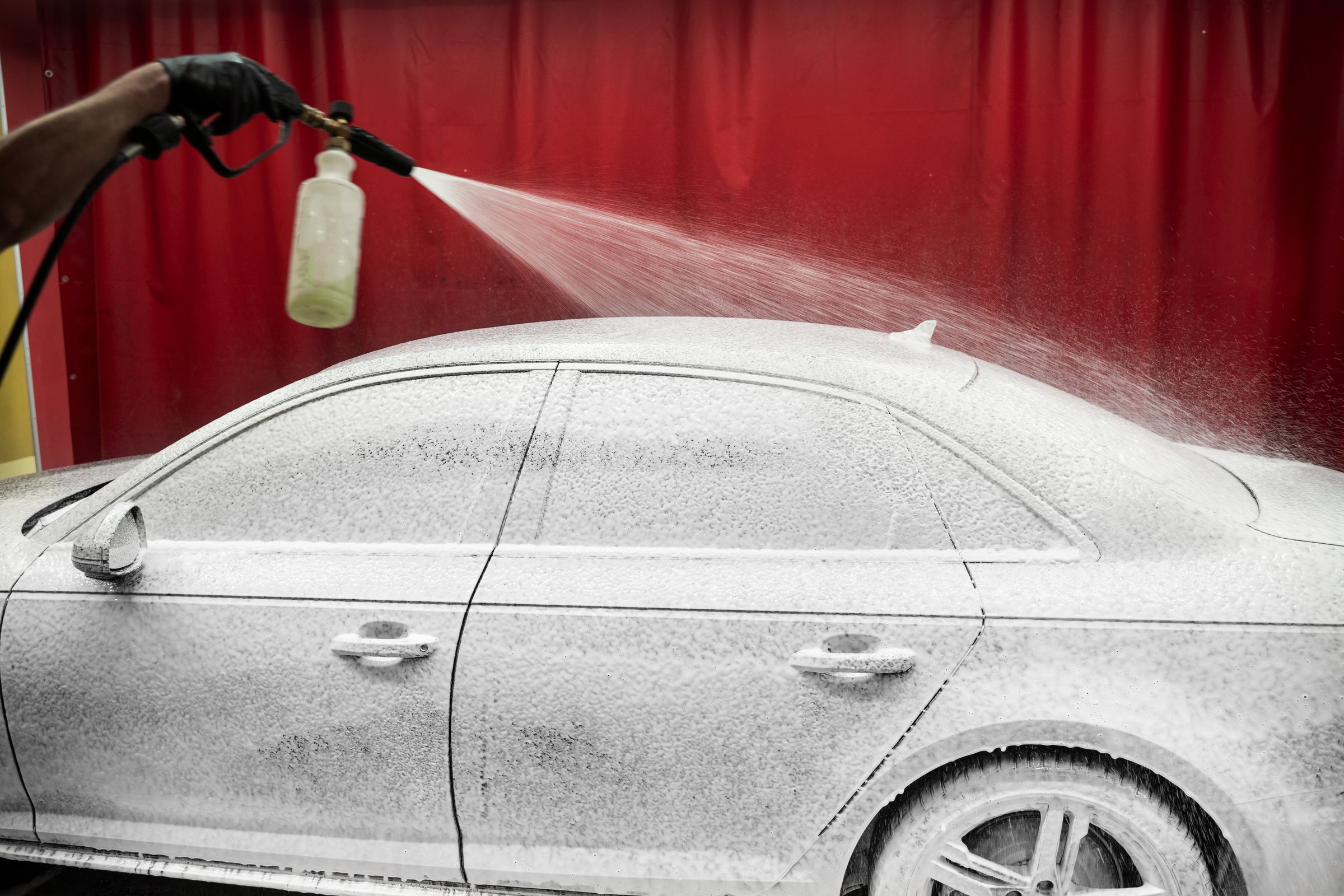 Car Foaming Stage. High-pressure snow foam application ensures deep cleaning and softens grime on car surface. Car gets covered in thick snow foam during initial washing phase for deep dirt removal