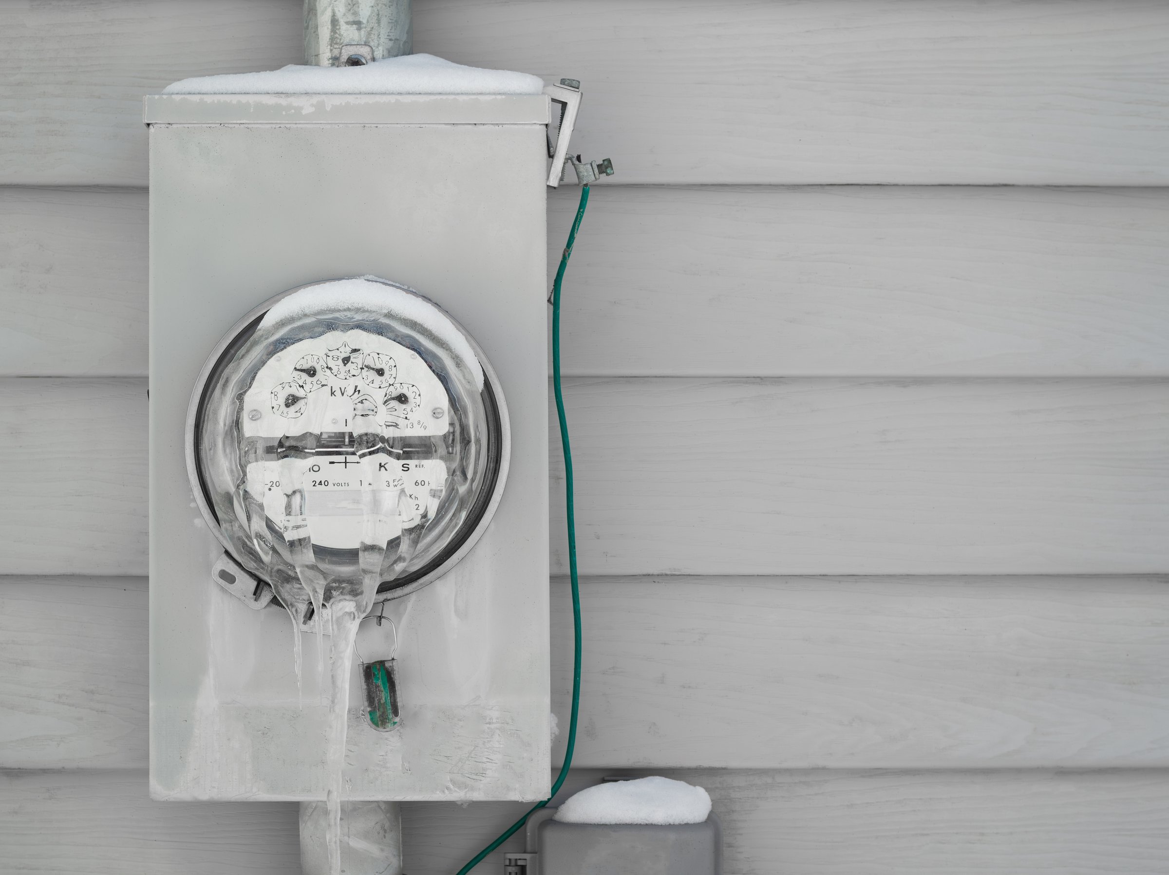 Frozen electrical utility meter on house  exterior siding.