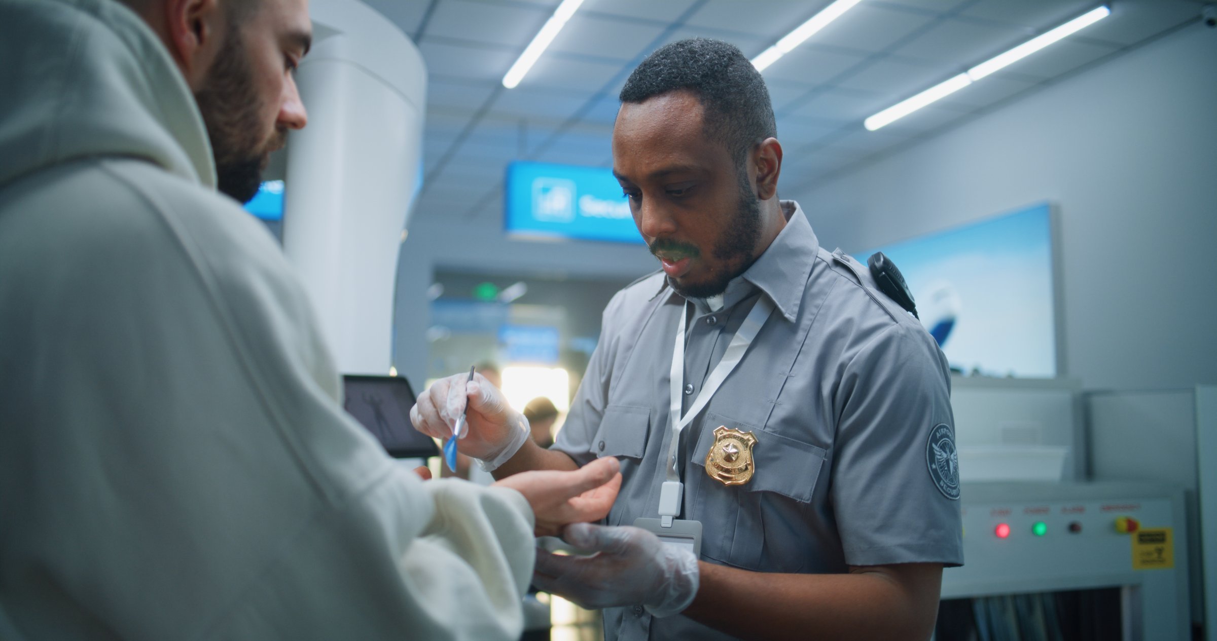 Airport Terminal: African American Security Officer Conducts TSA Hand Swab Screening with Brush to Adult Man for Plane Flight. ETD Procedure to Identify Traces of Explosive Materials. Medium Close Up.