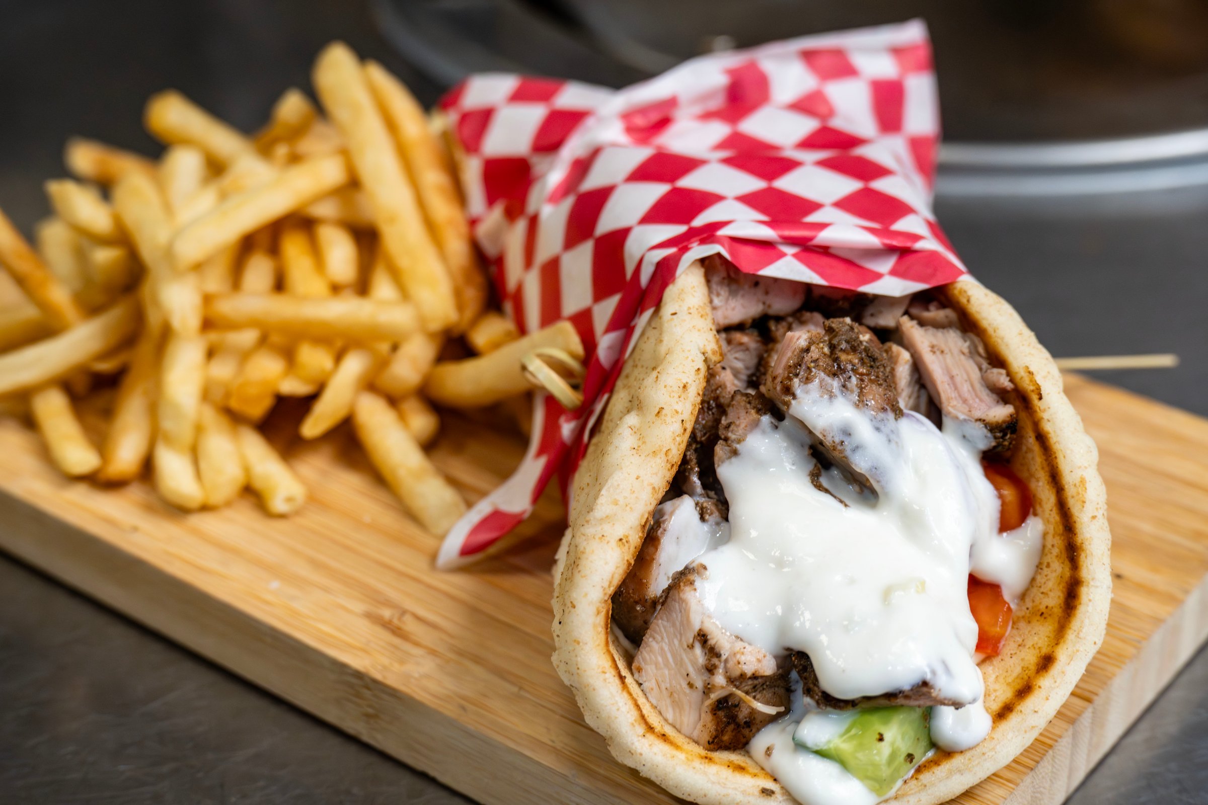 Chicken shawarma in a pita bread with cucumber, tomato onion and tzatziki with a side of fries