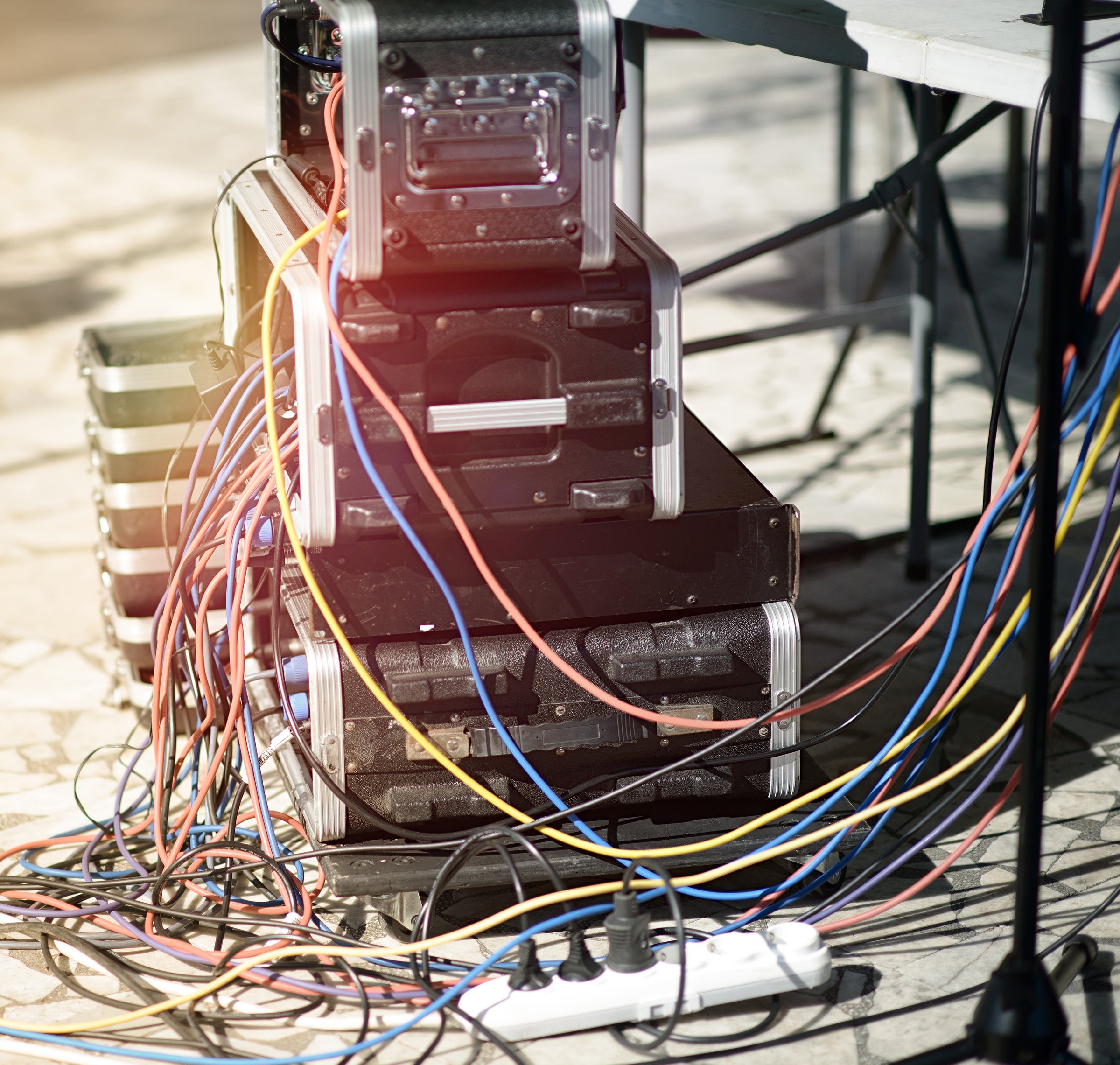 Intricate network of colorful cables connecting stacked audio gear, showcasing the technical intricacy of professional sound systems.