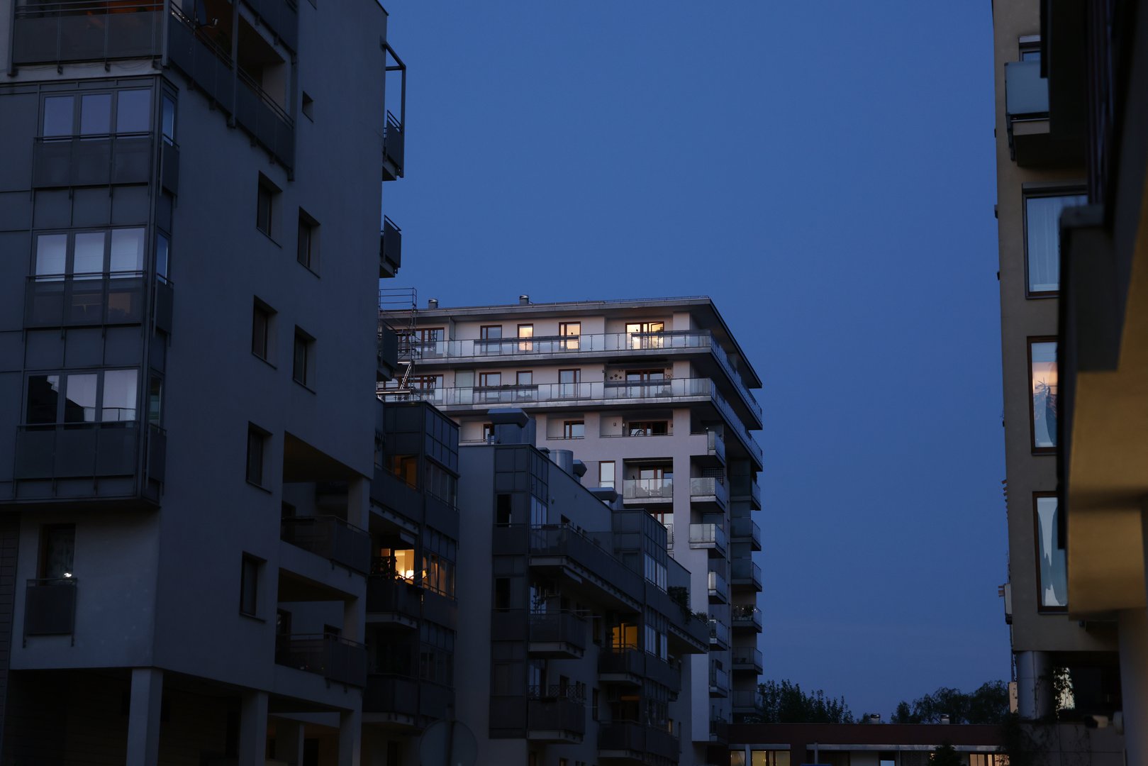 Modern apartment buildings at twilight. Warm interior light contrasts with the cool evening sky. Ideal for real estate, architecture, and urban lifestyle advertising. Clean lines and a tranquil mood.