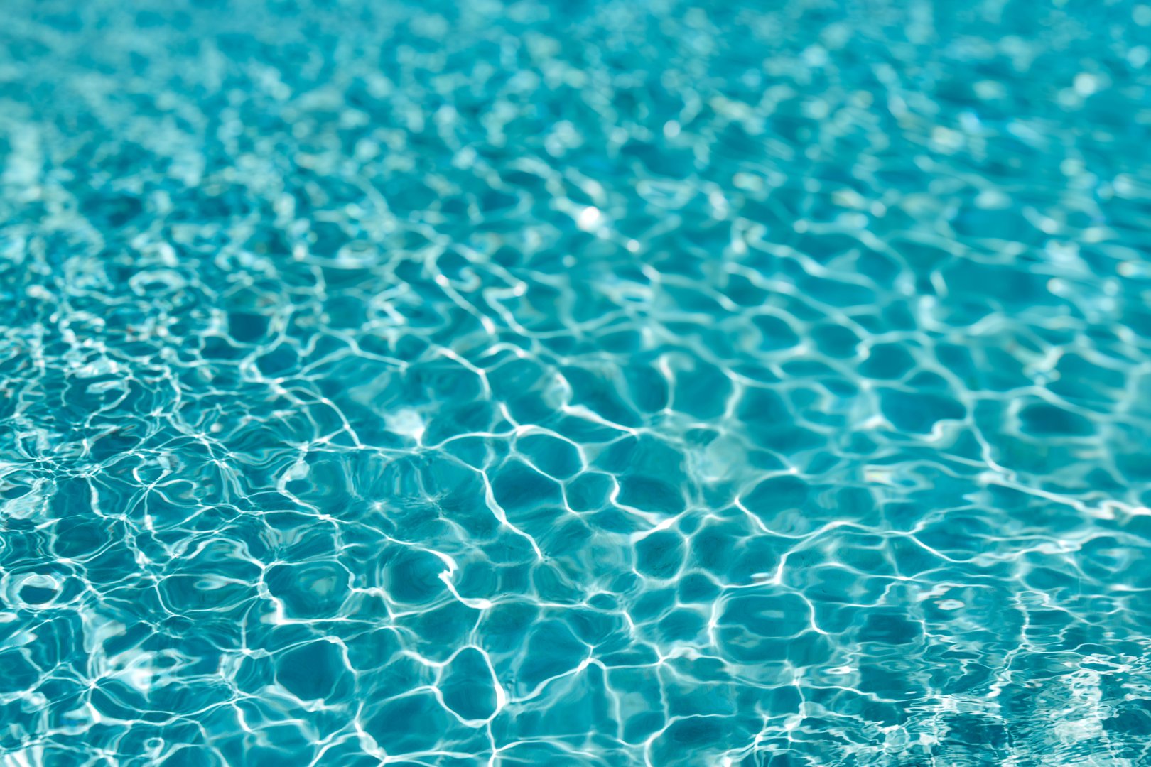 Background of rippled pattern of clean water in a blue swimming pool