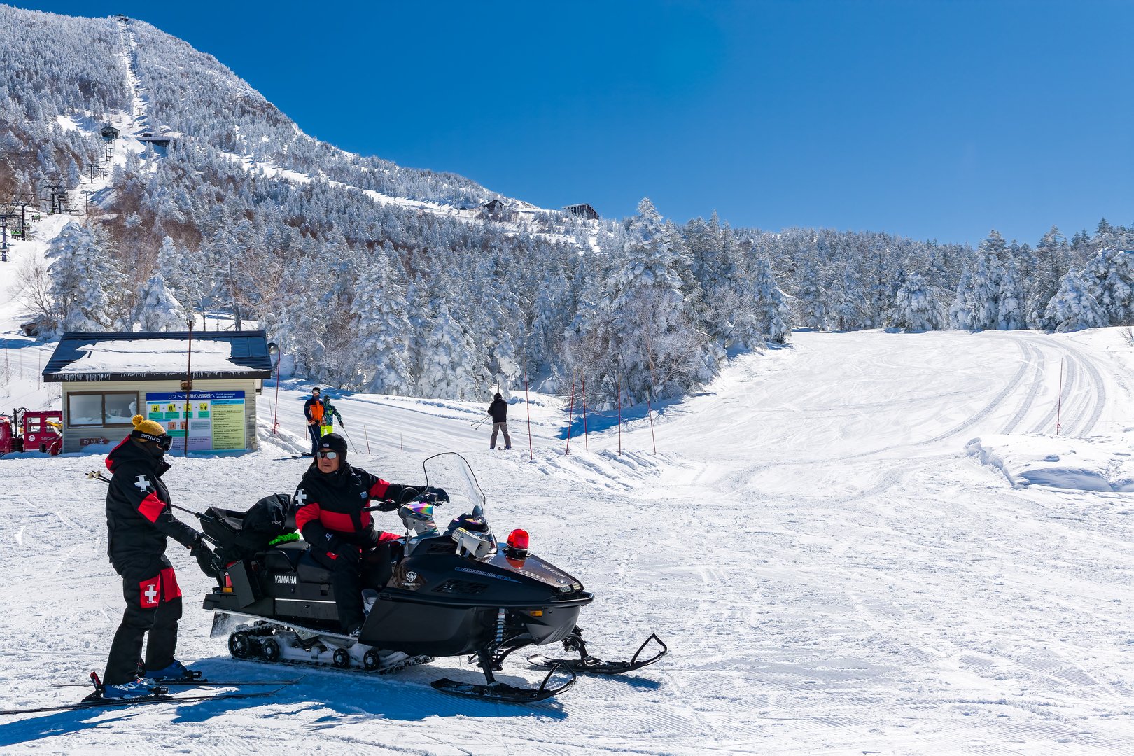 Ski patrol staff with a snowmobile on a snowy slope at Yokoteyama resort, Japan