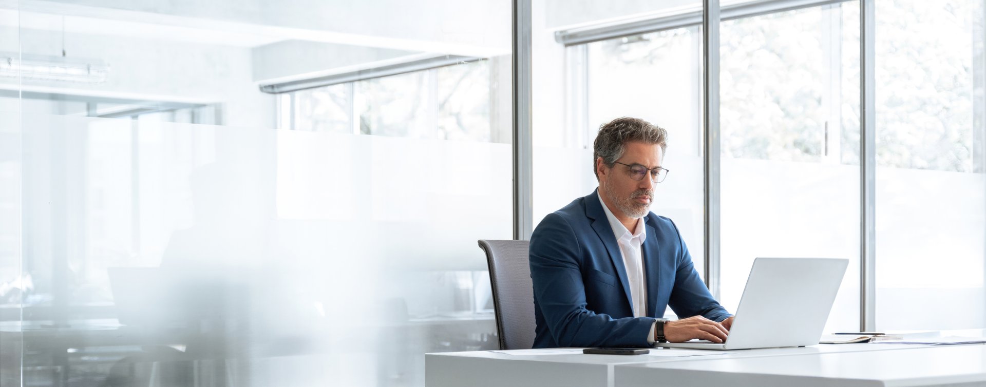 Professional investor manager using pc laptop computer sitting at desk workplace in office. Busy senior financial expert analyst in suit working on concentrated on trade strategy. Banner, copy space