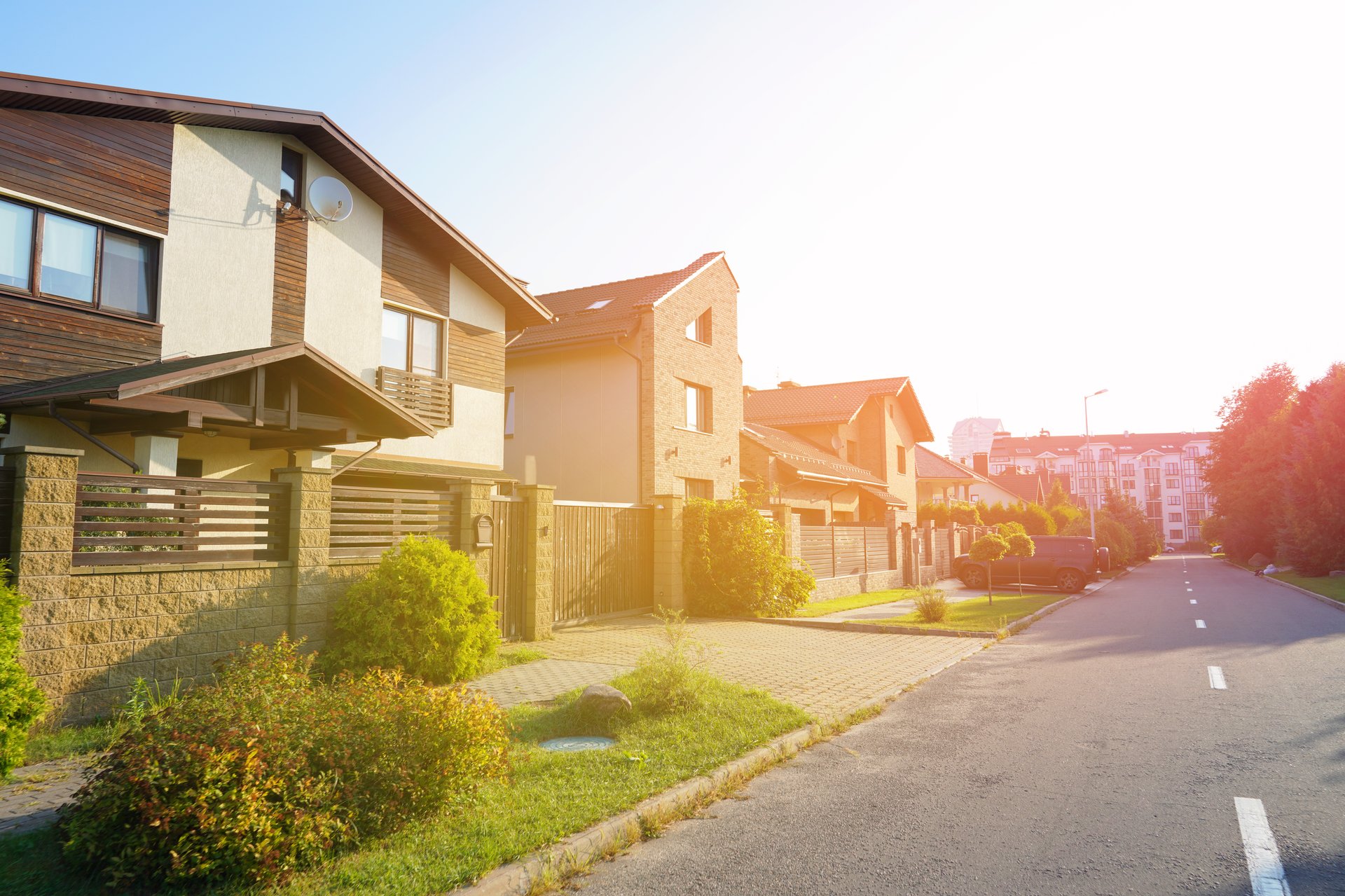Street in residential area in suburb on sunset. Rows of houses along road. Family house outside city. Dream country home. Home outside the city. Road at village. Trees and green lawn at Villa.